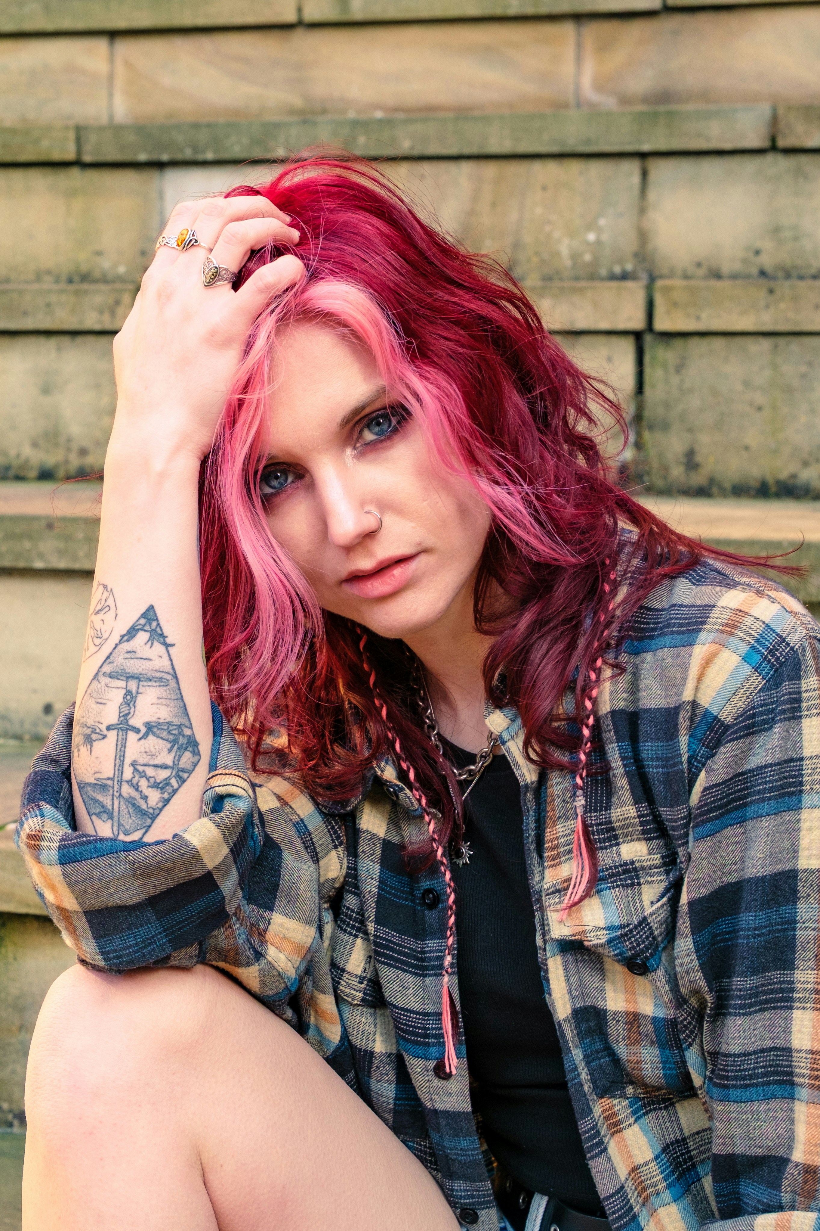 A woman with pink and red hair poses on stairs.