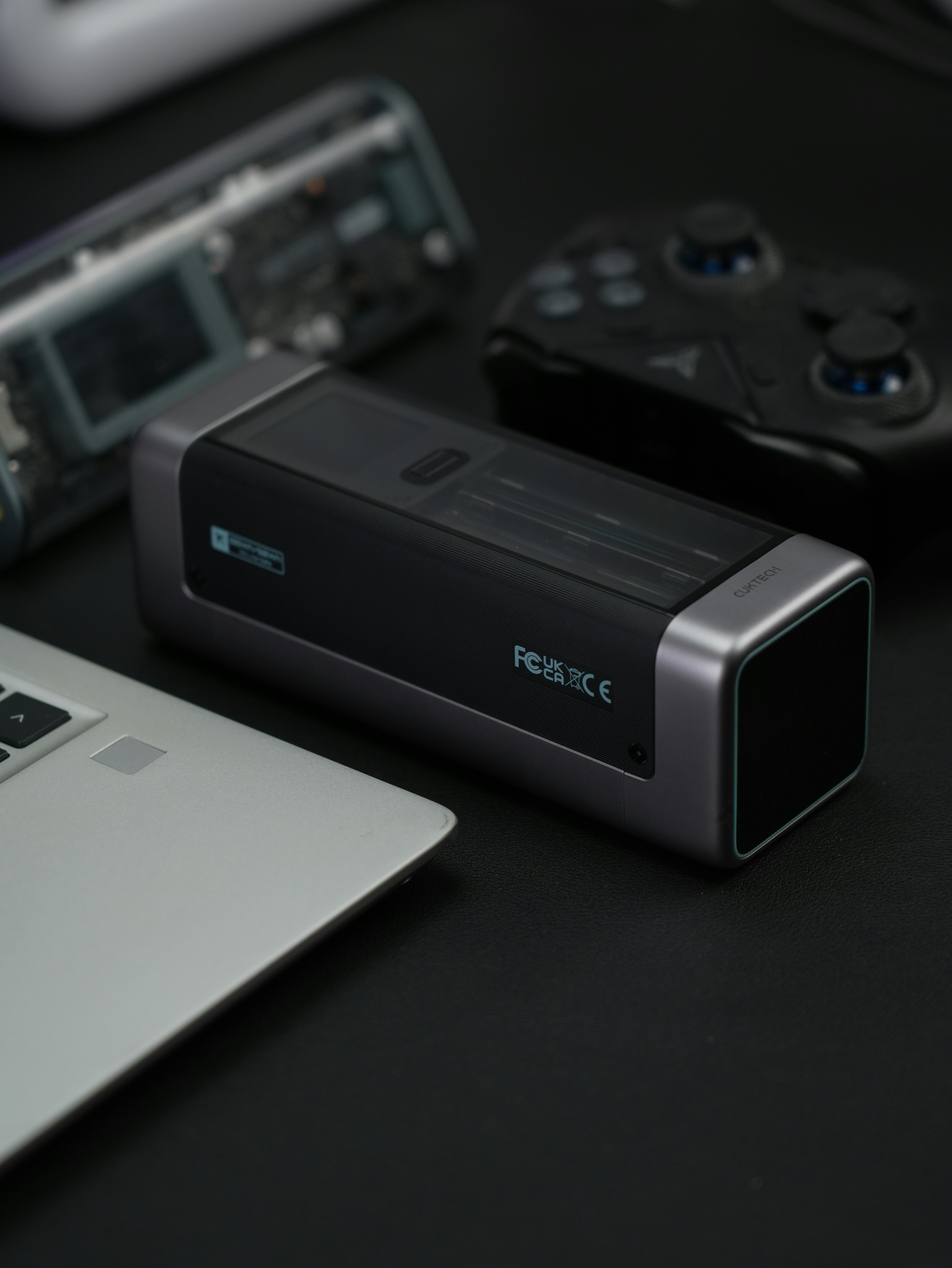 Electronics and a controller lie on a dark surface.