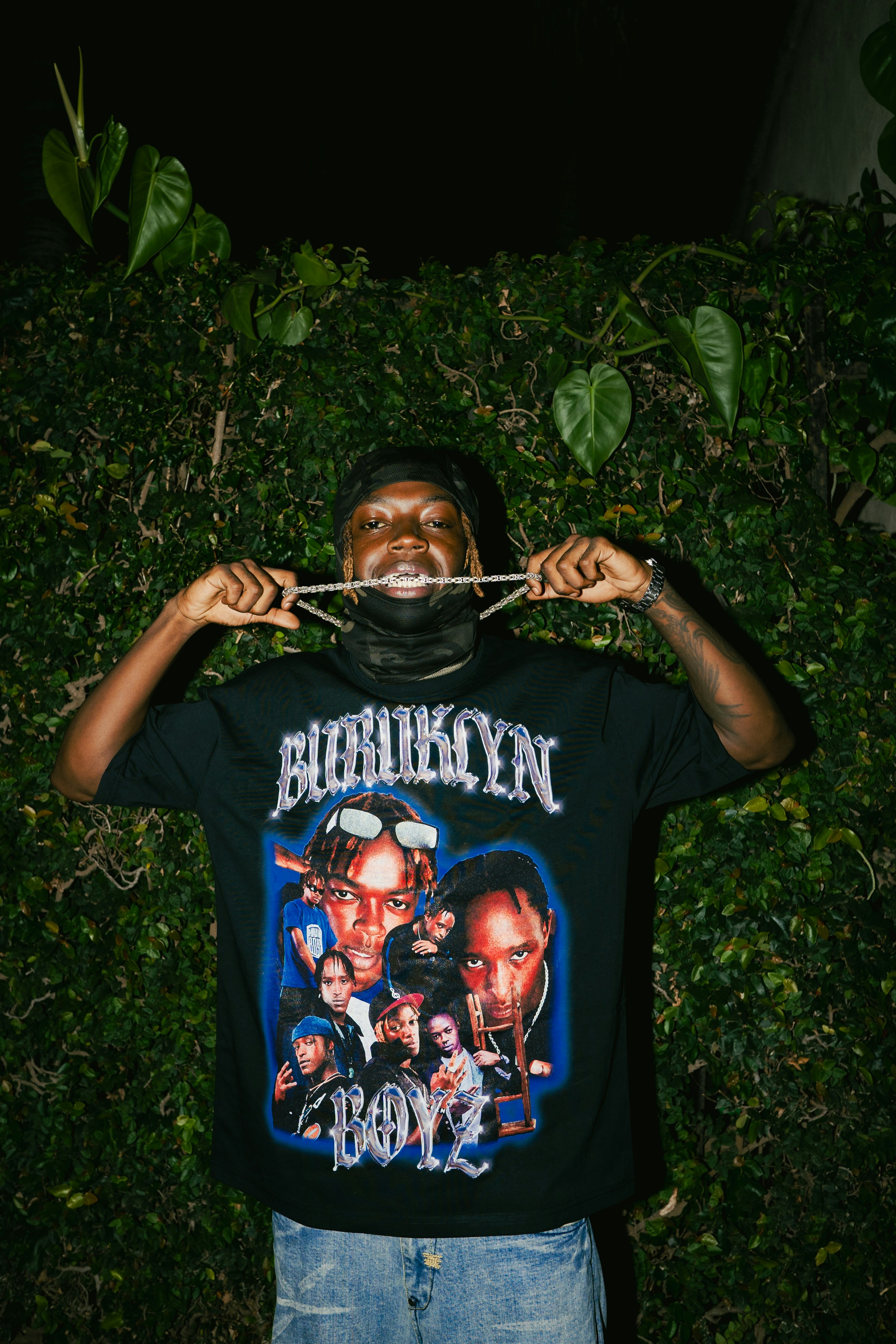 Man wearing a brooklyn t-shirt holds up his necklace.