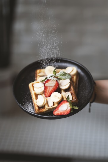 Powdered sugar is sprinkled on a waffle.