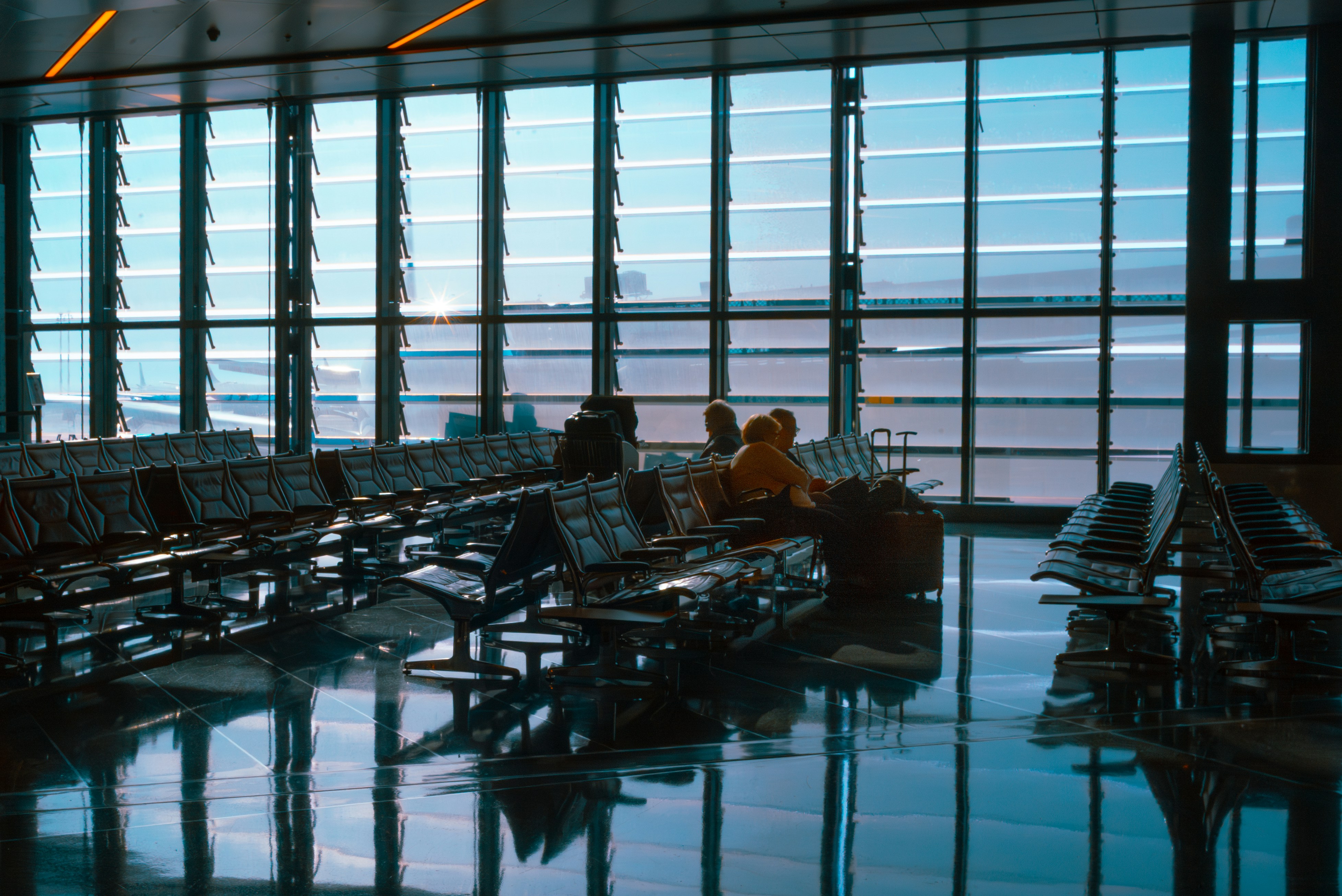 People sit in a bright and spacious airport terminal., 
