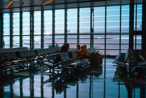 People sit in a bright and spacious airport terminal.