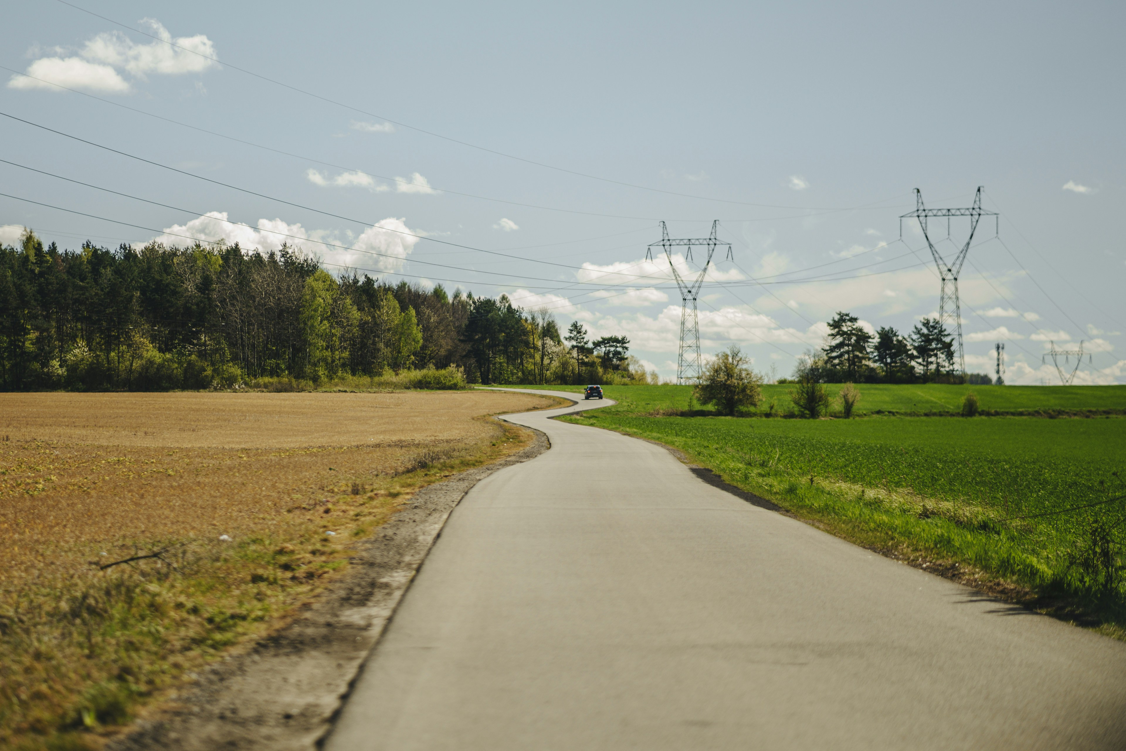 A winding road leads through fields and trees.