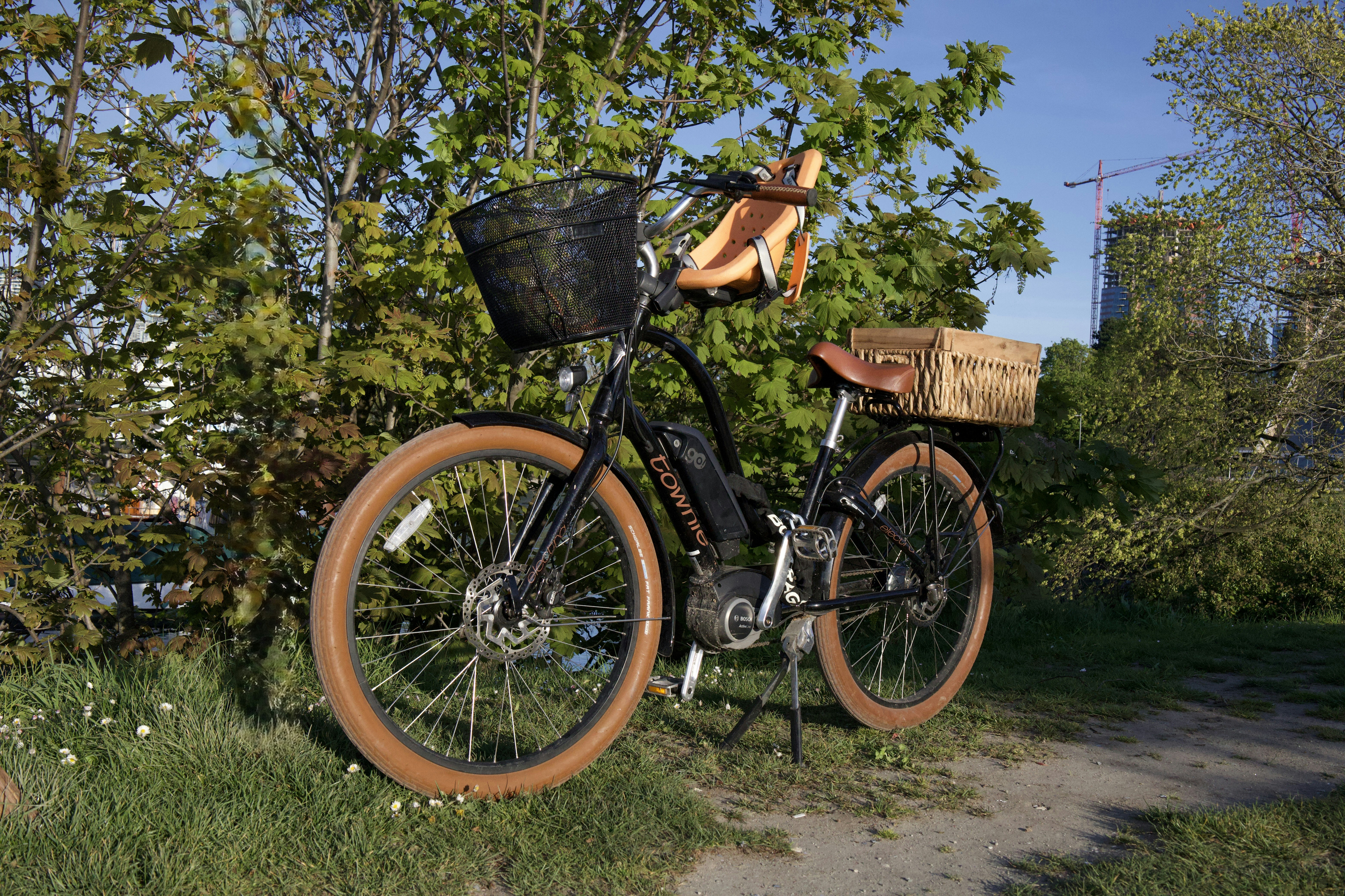 A bicycle with baskets is resting on grass.