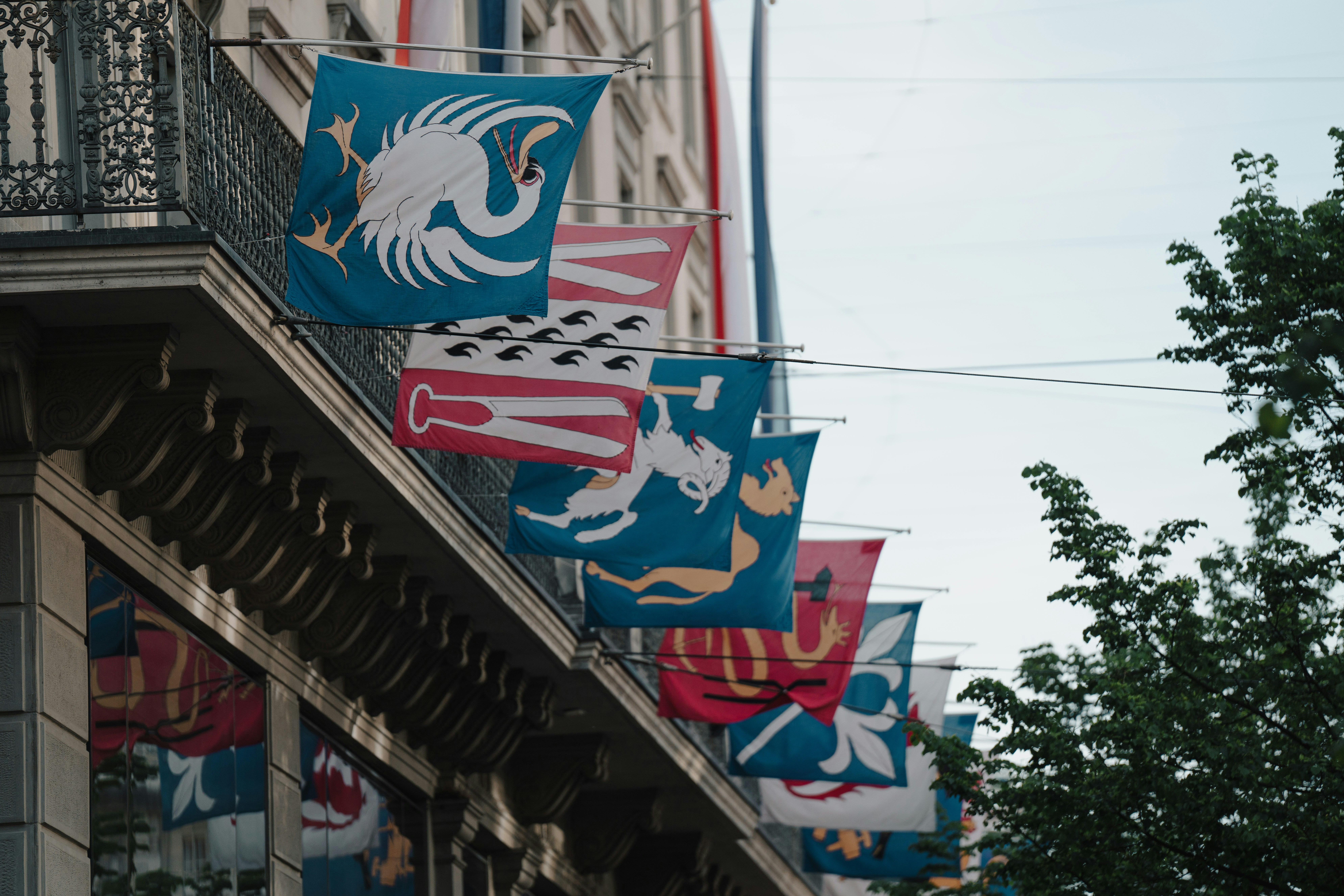 Flags with heraldic designs hang from a building.