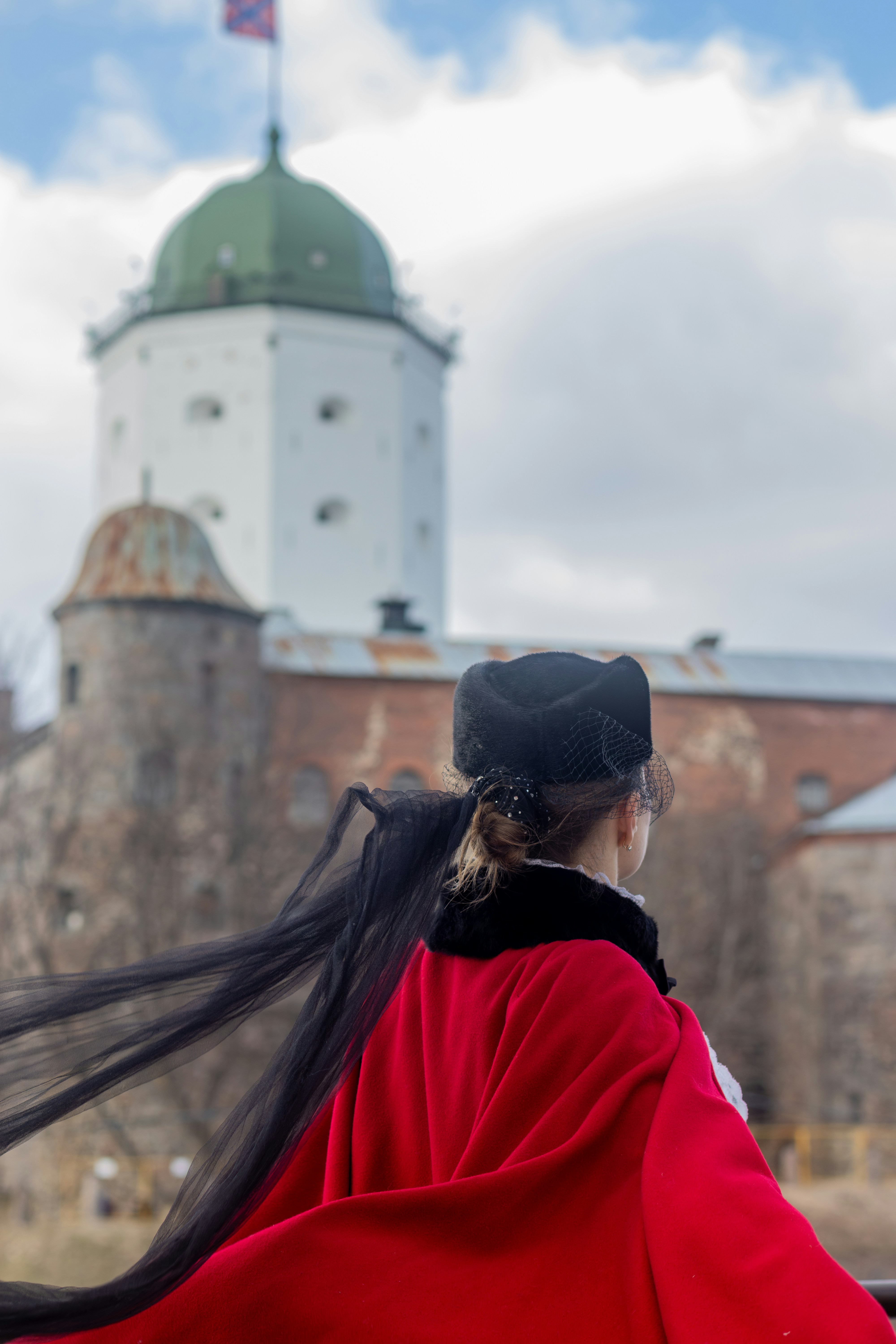 Frau mit Umhang blickt auf ein Schloss.