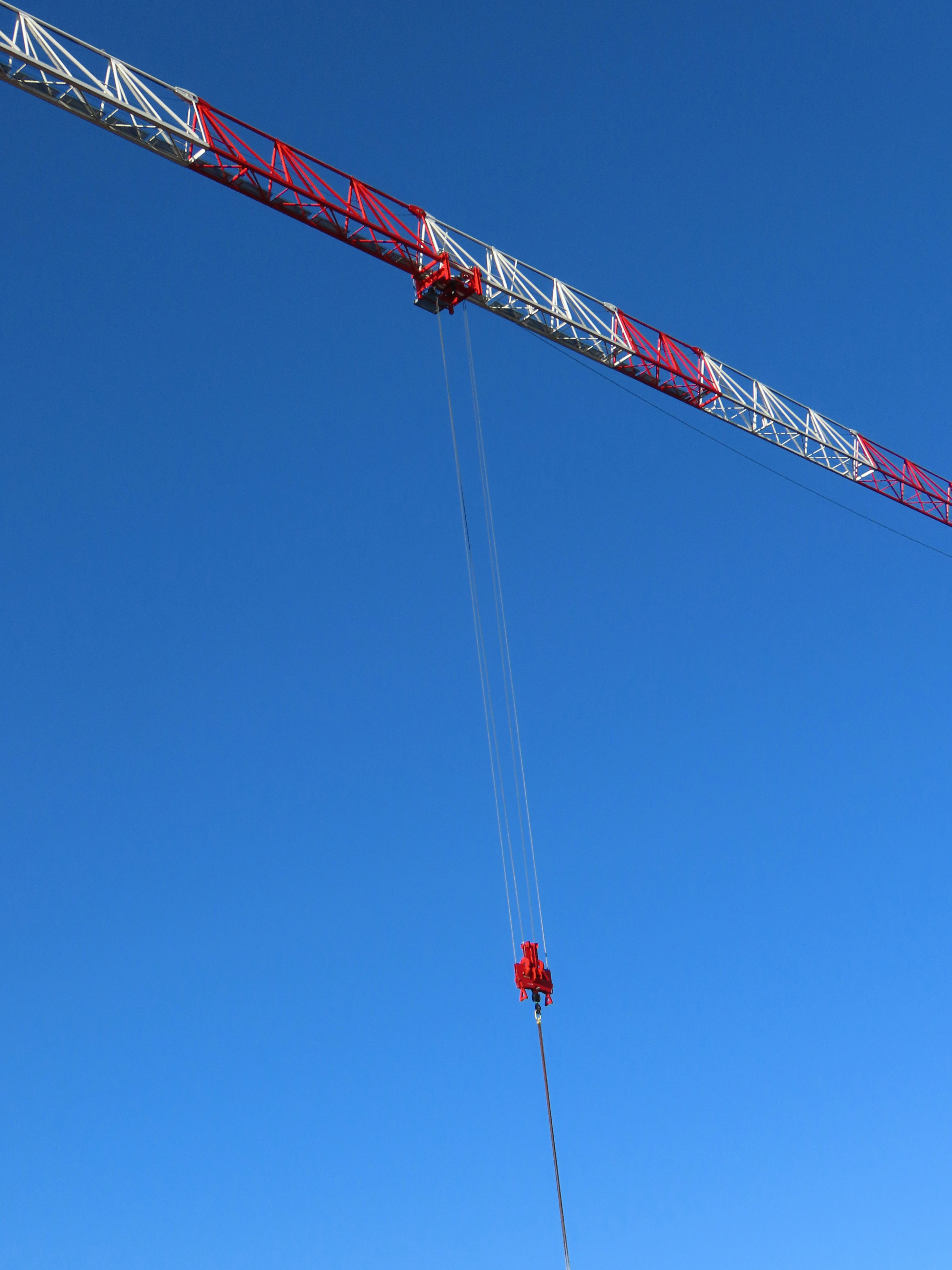 A red and white construction crane against blue sky.