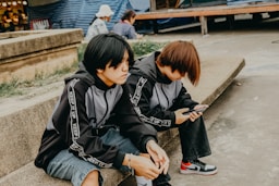 Two people sit side-by-side on a ledge.