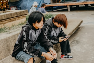 Two people sit side-by-side on a ledge.
