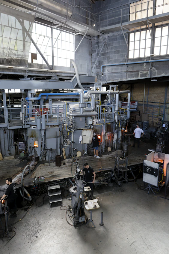 A glassblowing studio with equipment and workers