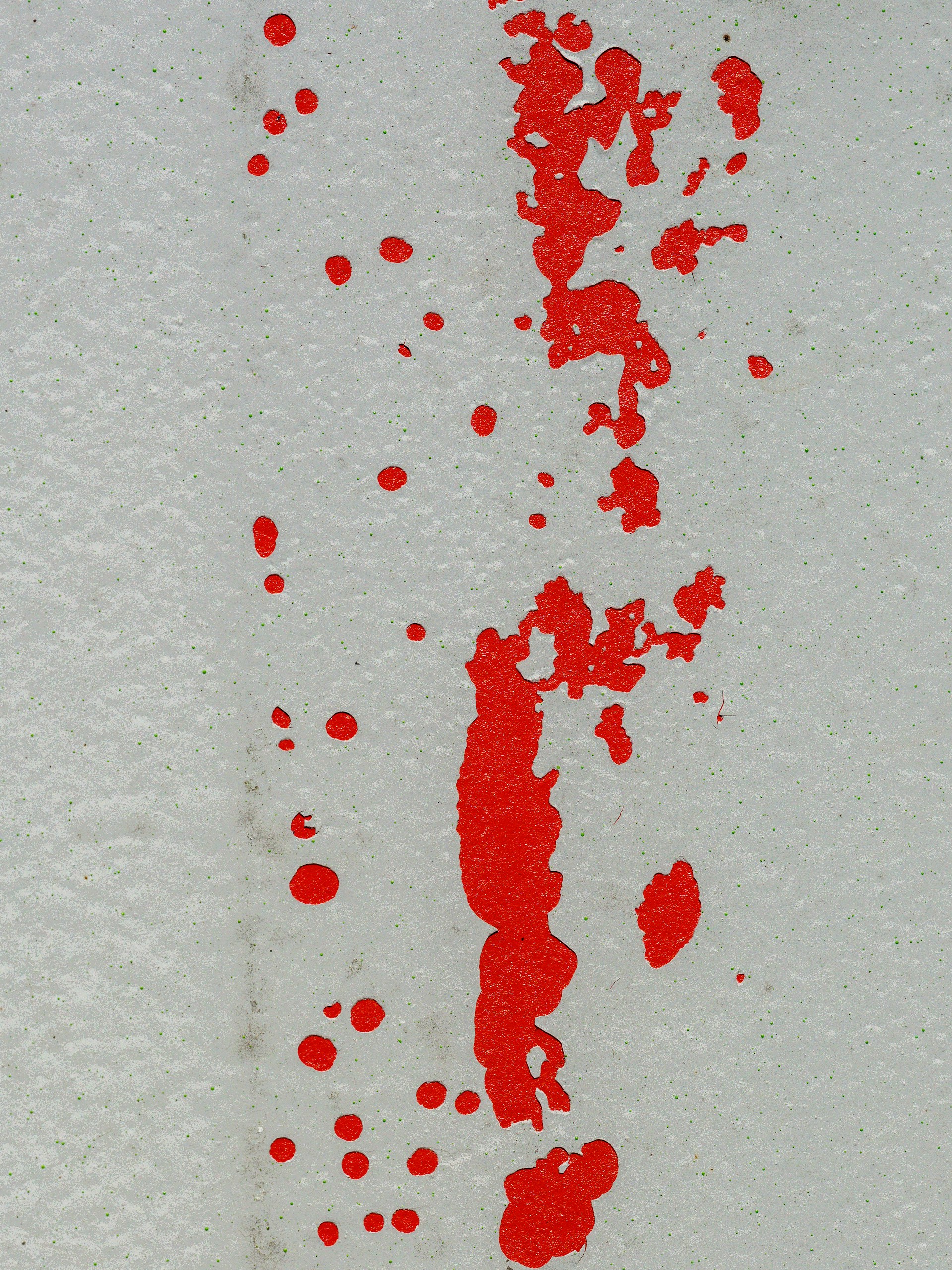 Red paint splatters and streaks on a white wall.