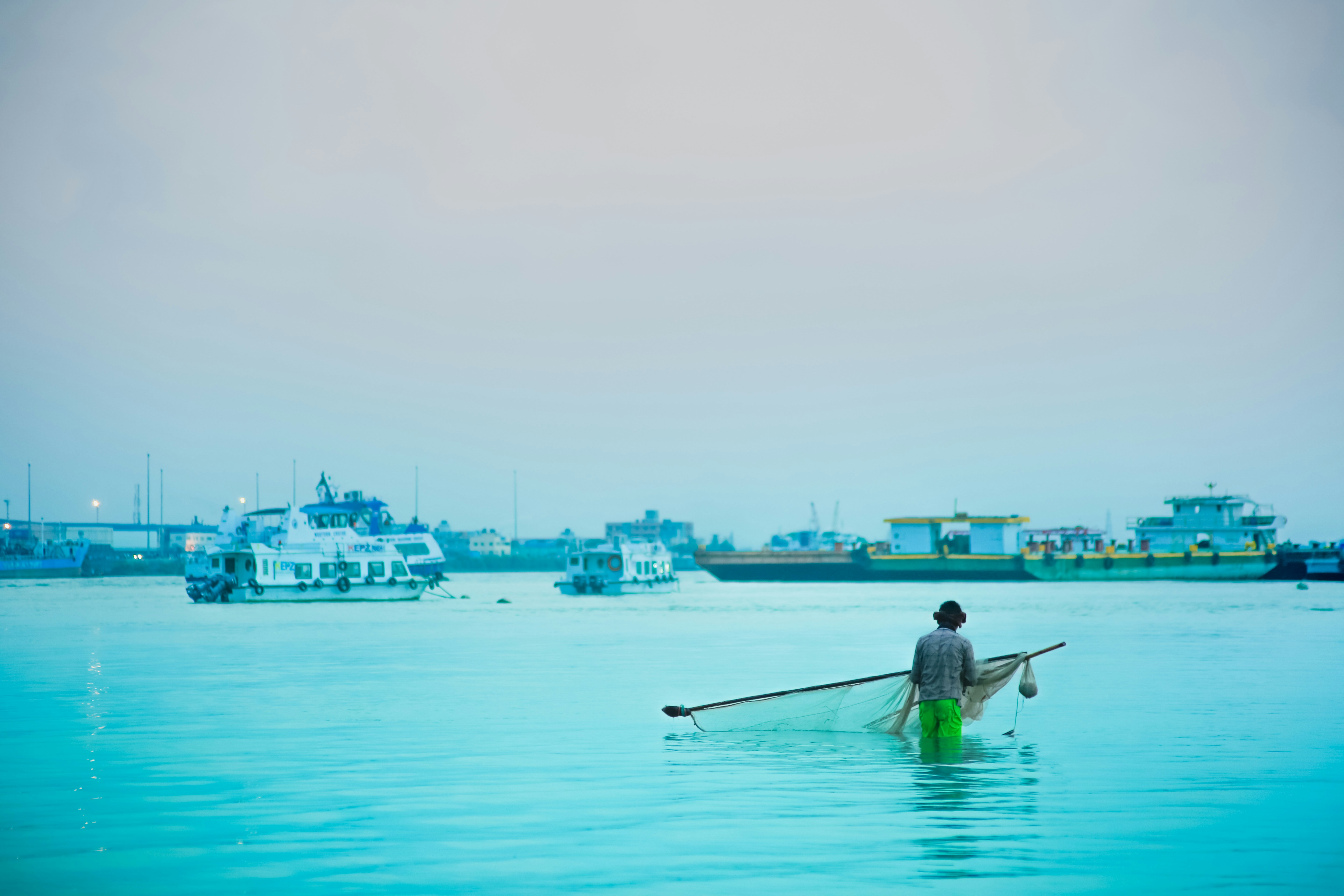 A fisherman nets in the calm, blue waters.