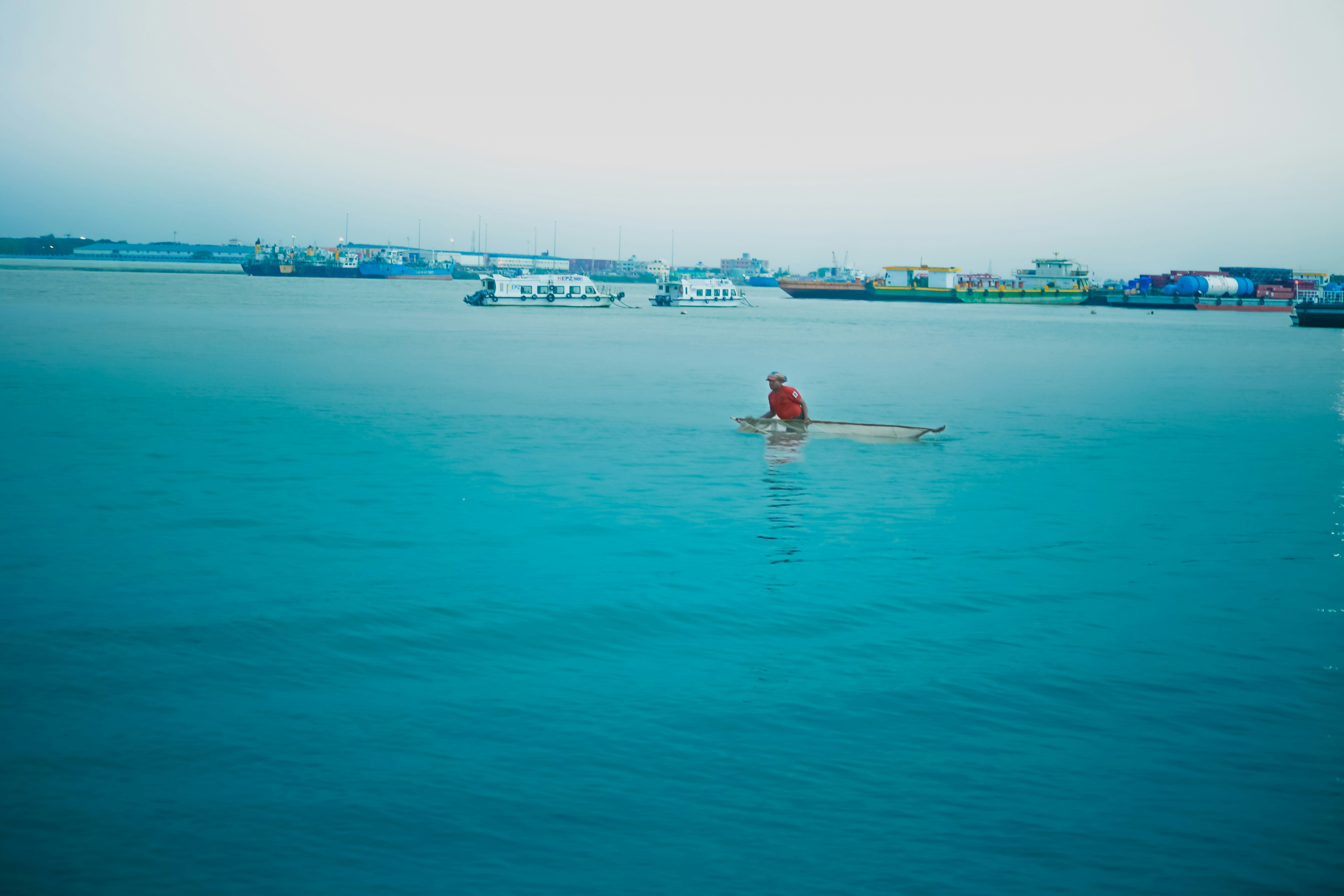 A red sailboat floats on the ocean.