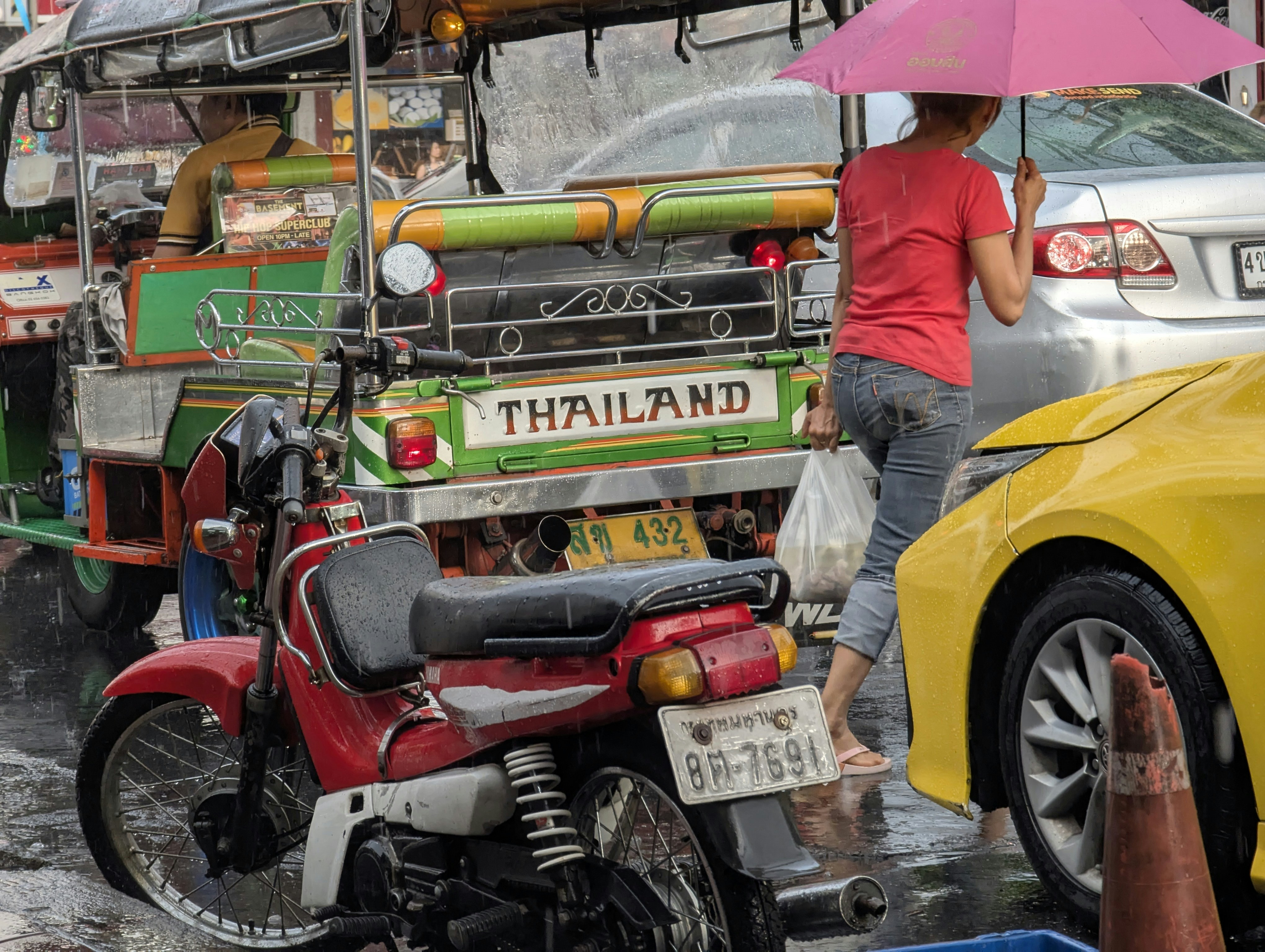 A woman with an umbrella in thailand traffic.