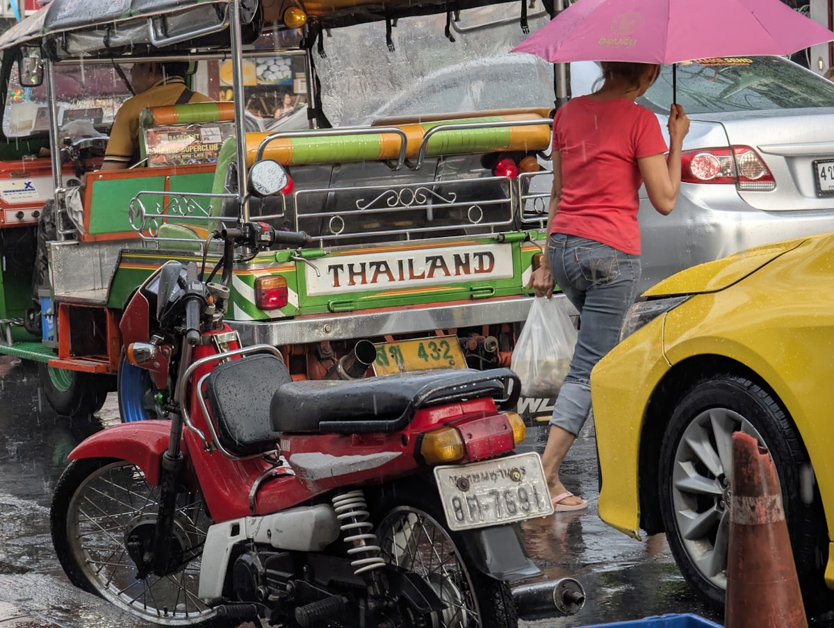 A woman with an umbrella in thailand traffic.