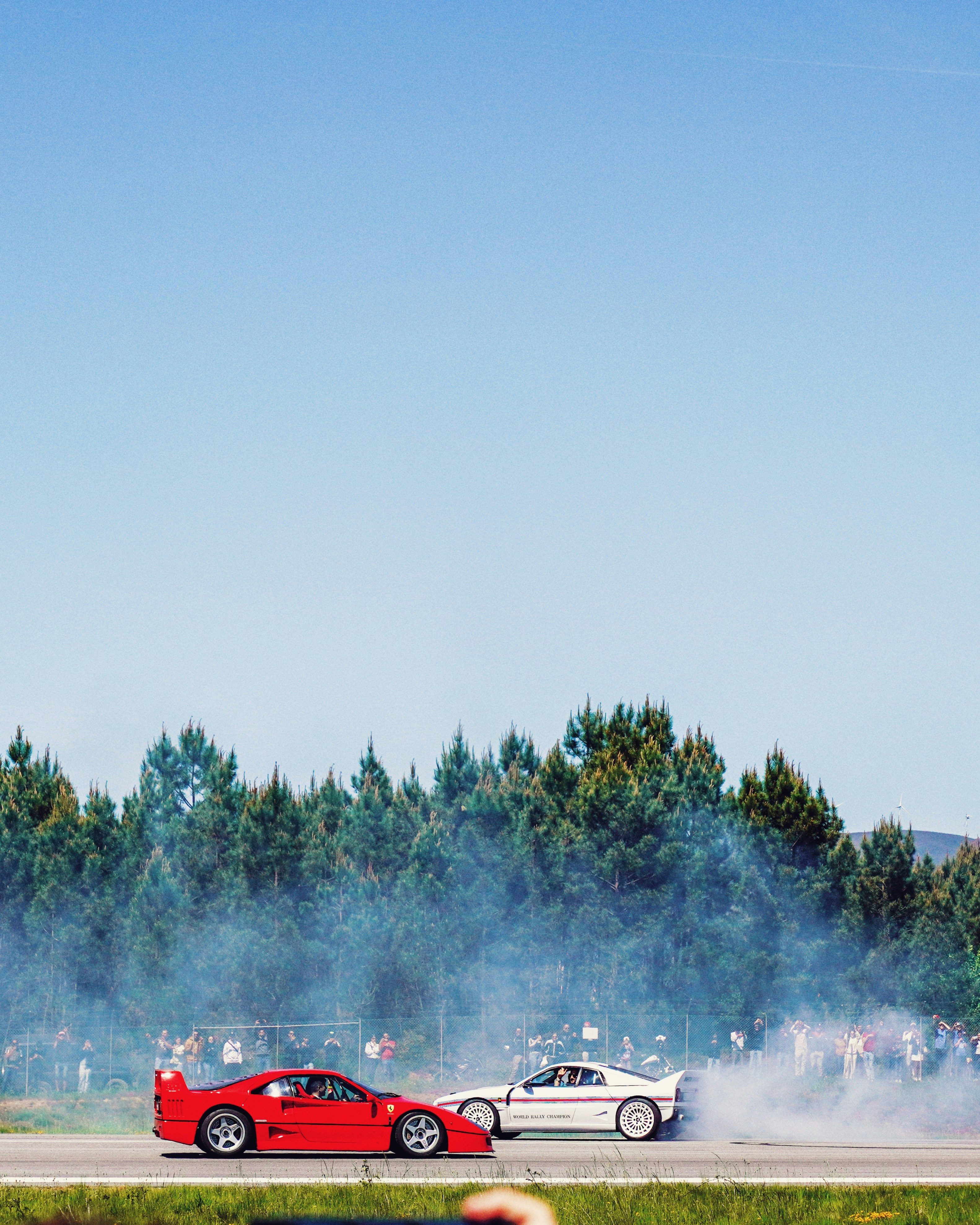 Two sports cars smoke tires on a track.
