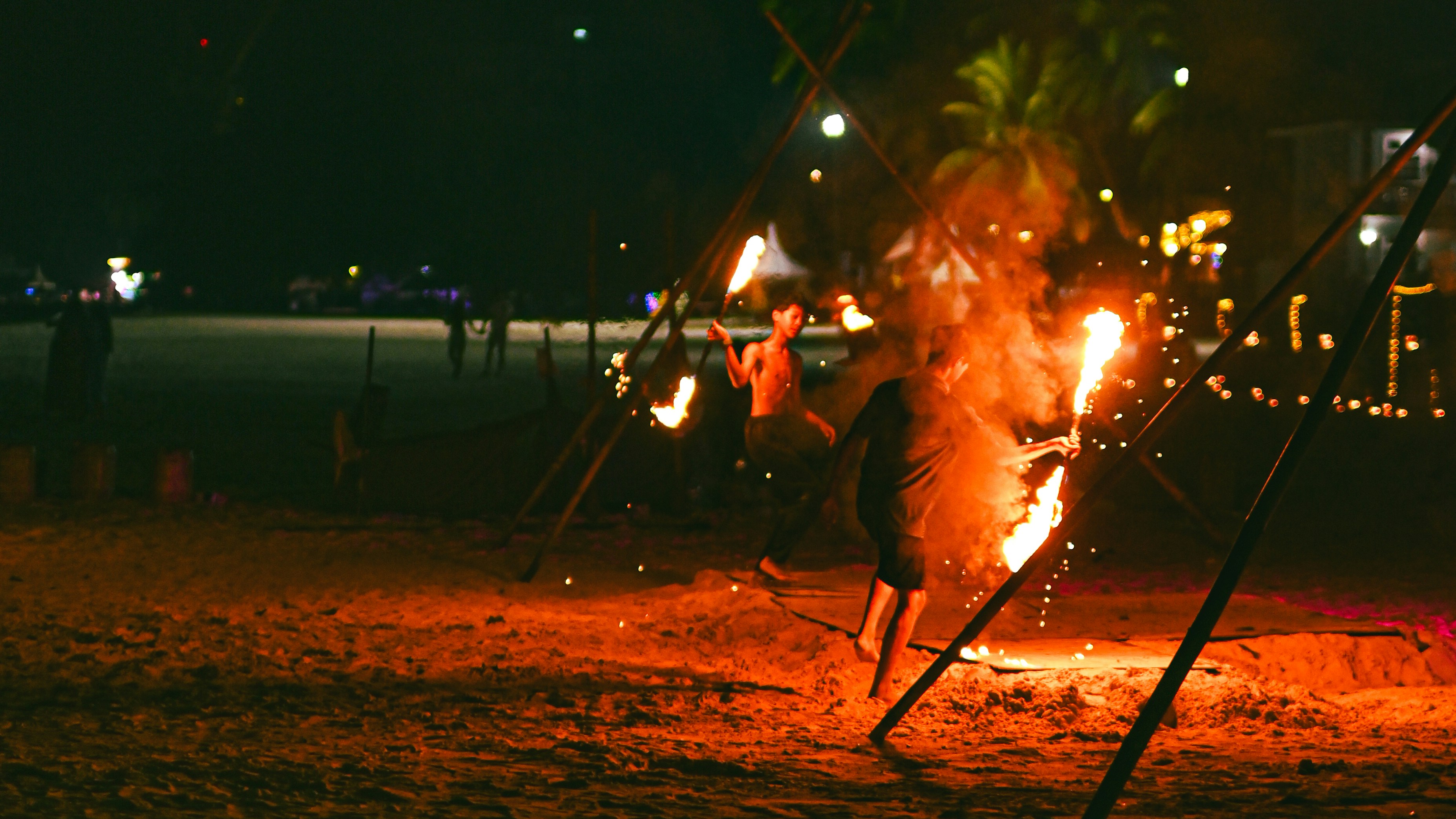 Des artistes de feu dansent sur la plage la nuit.