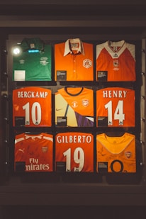 Arsenal football jerseys are displayed in a glass case.