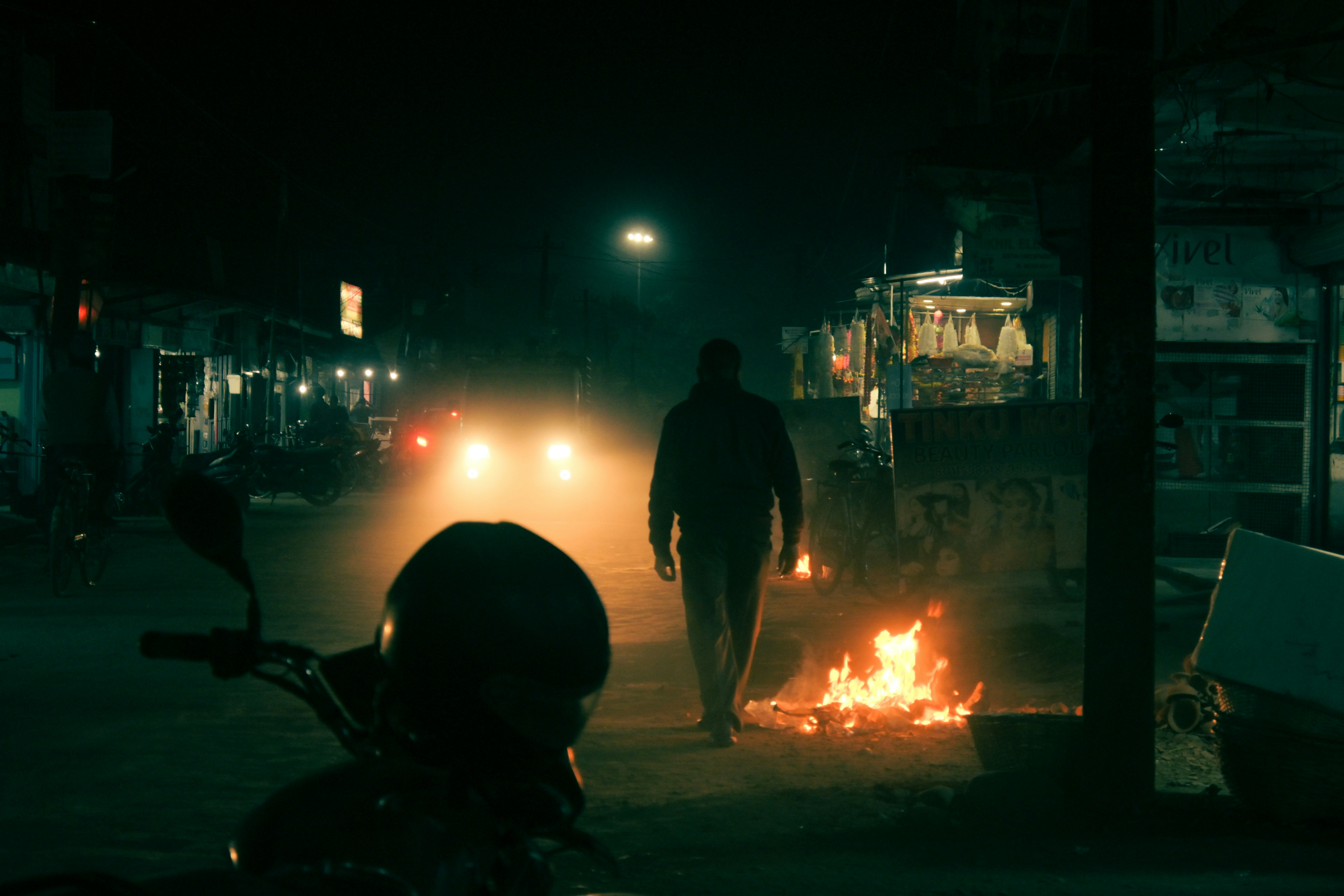 La nuit, un homme marche dans une rue sombre.
