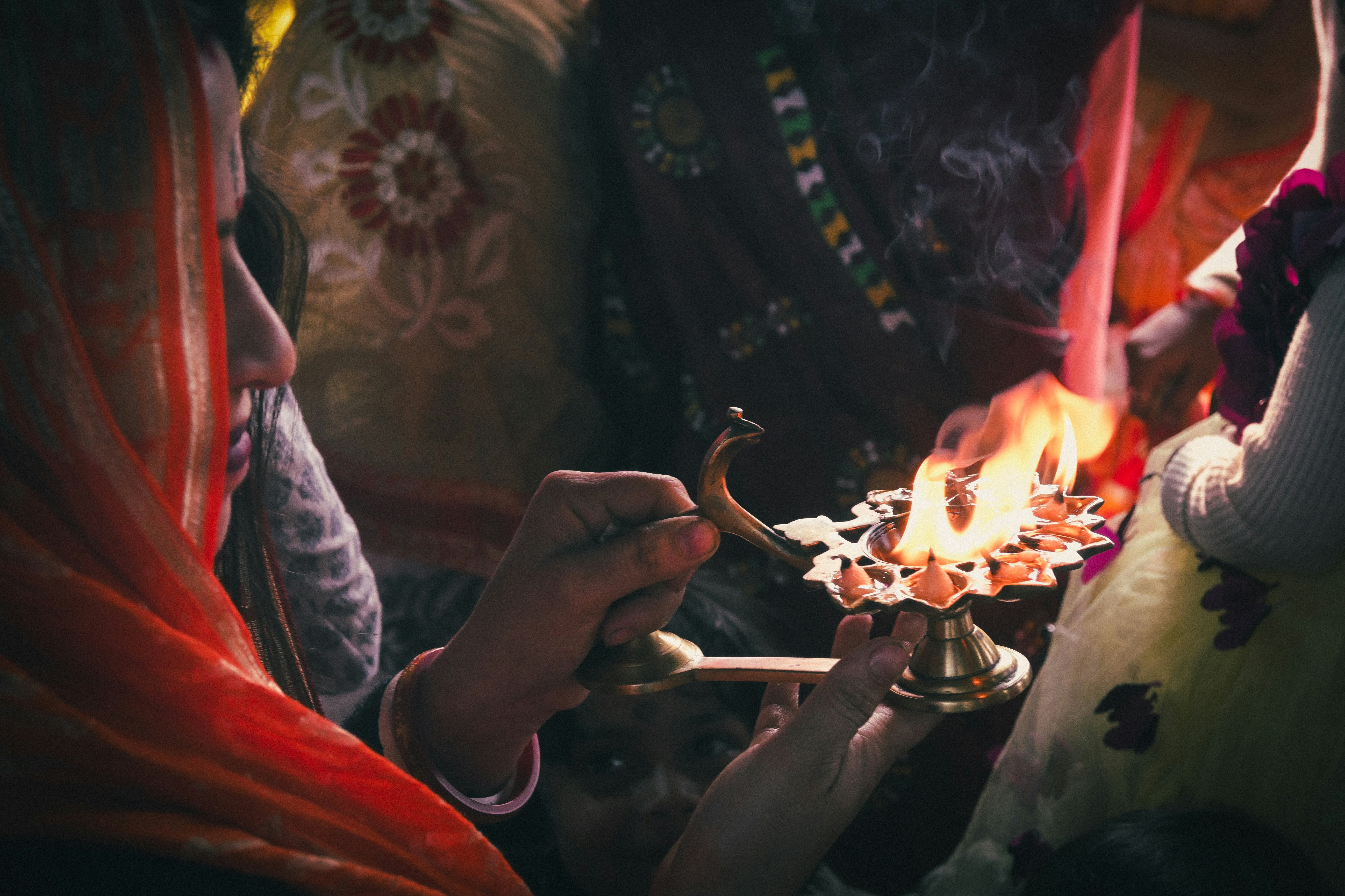 Woman holds a lamp during a religious ceremony.