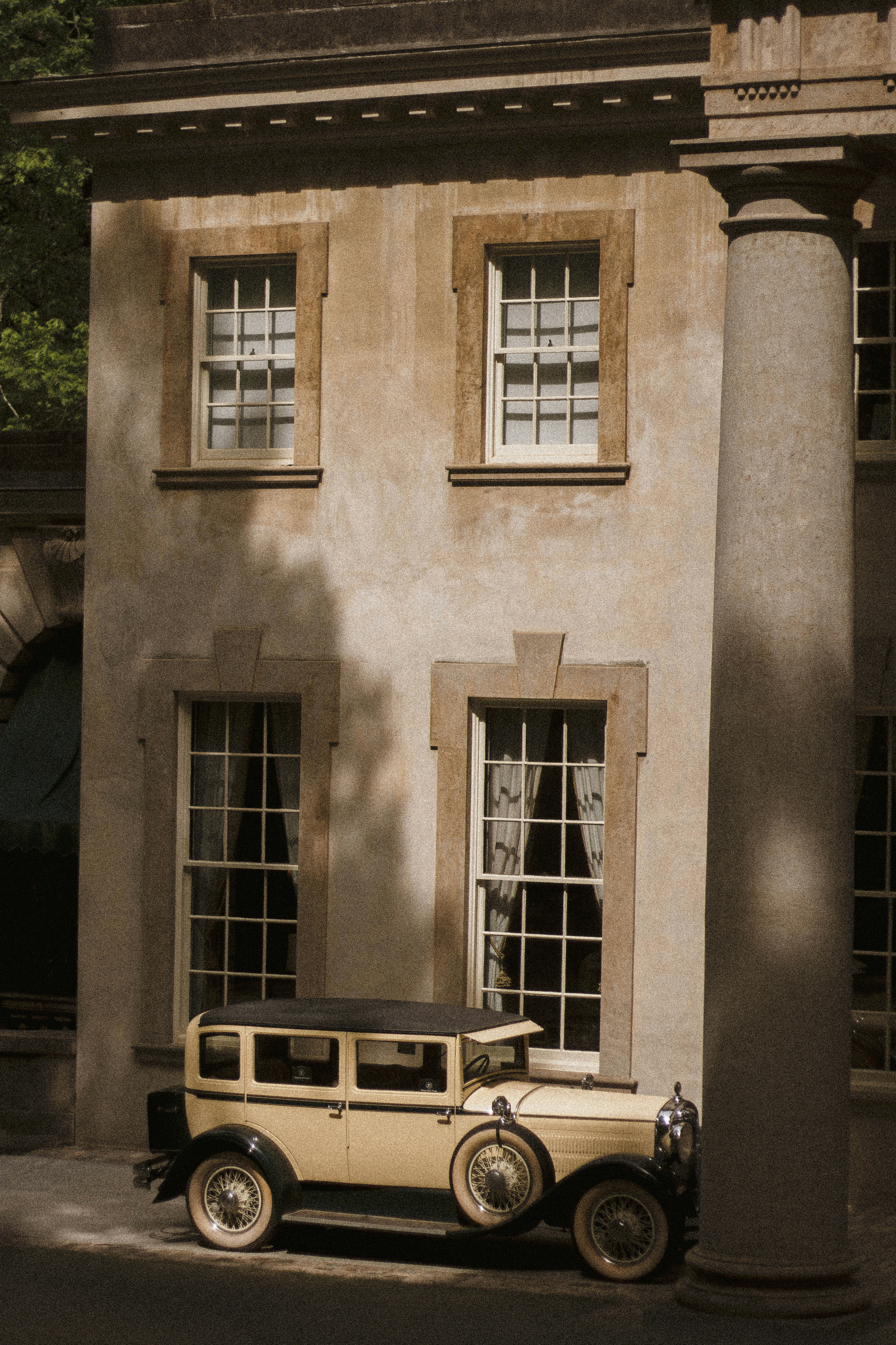 クラシックな建物の近くにビンテージカーが停まっています。