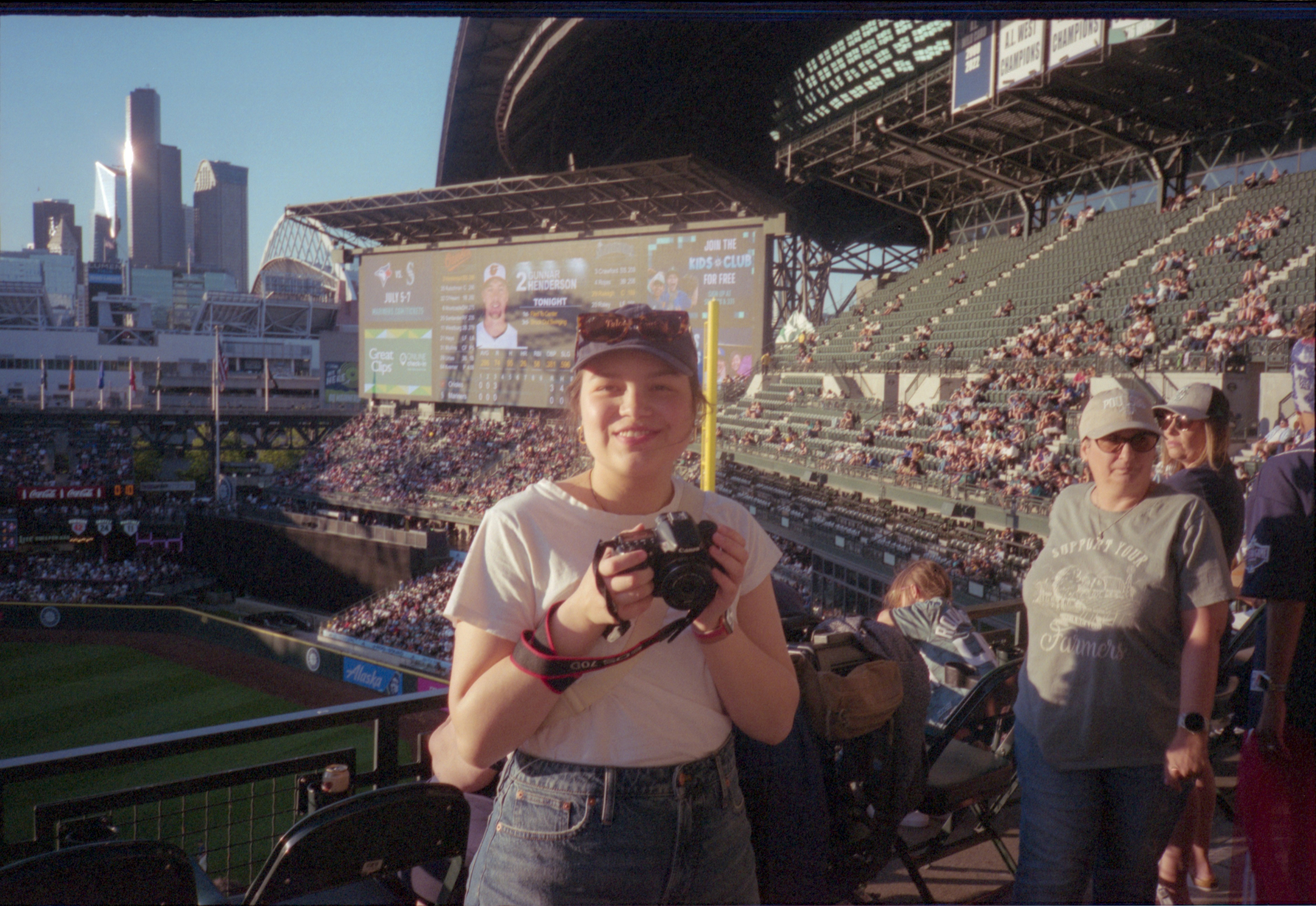 La donna posa con una macchina fotografica a una partita di baseball.