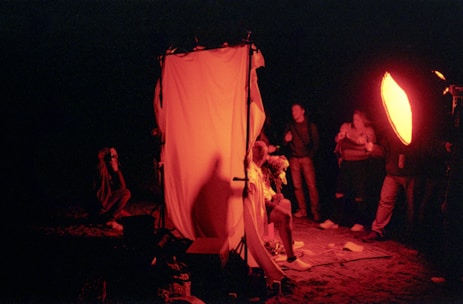 People filming a scene lit with red lights.