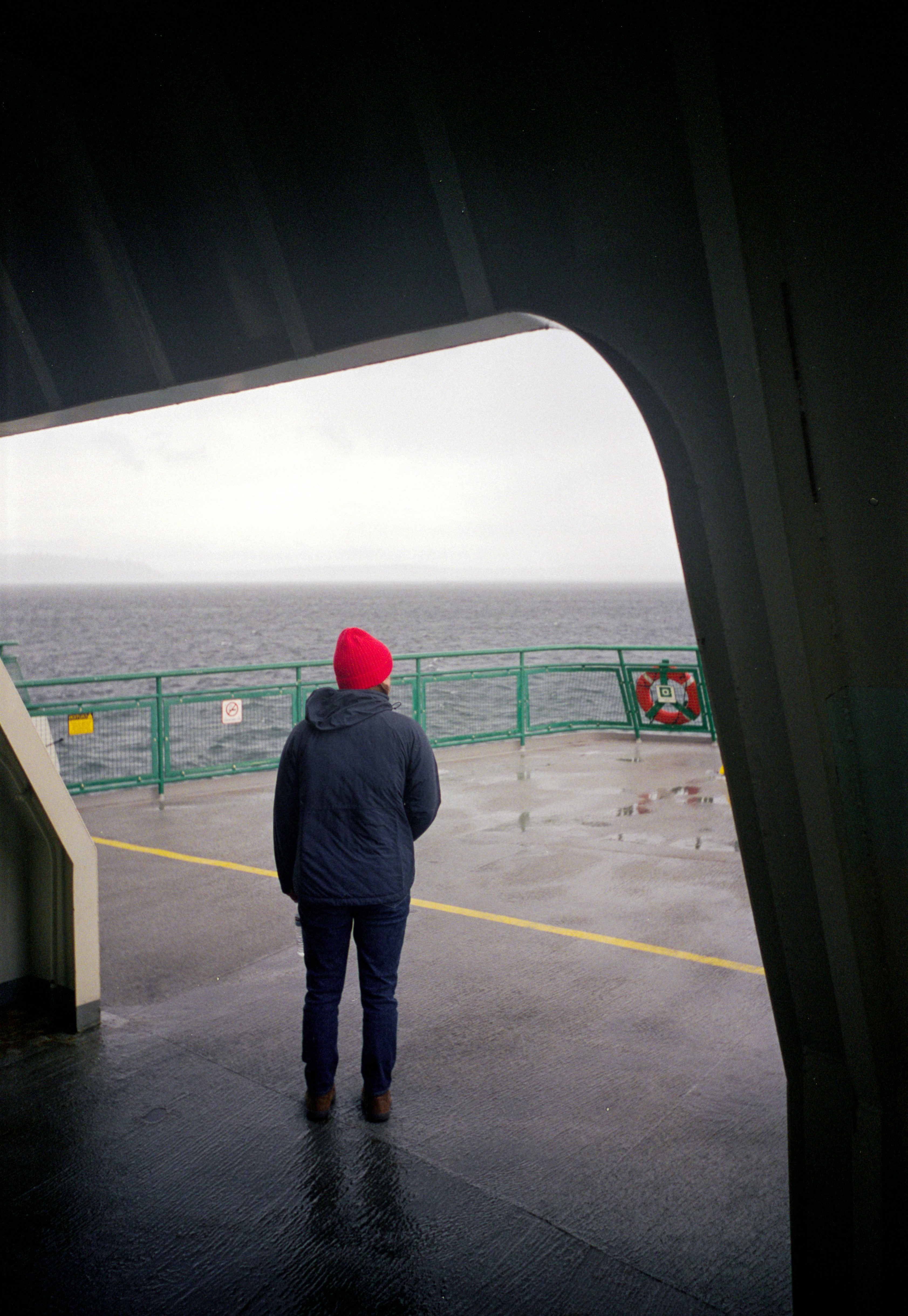 Persona con cappello rosso guarda il mare.