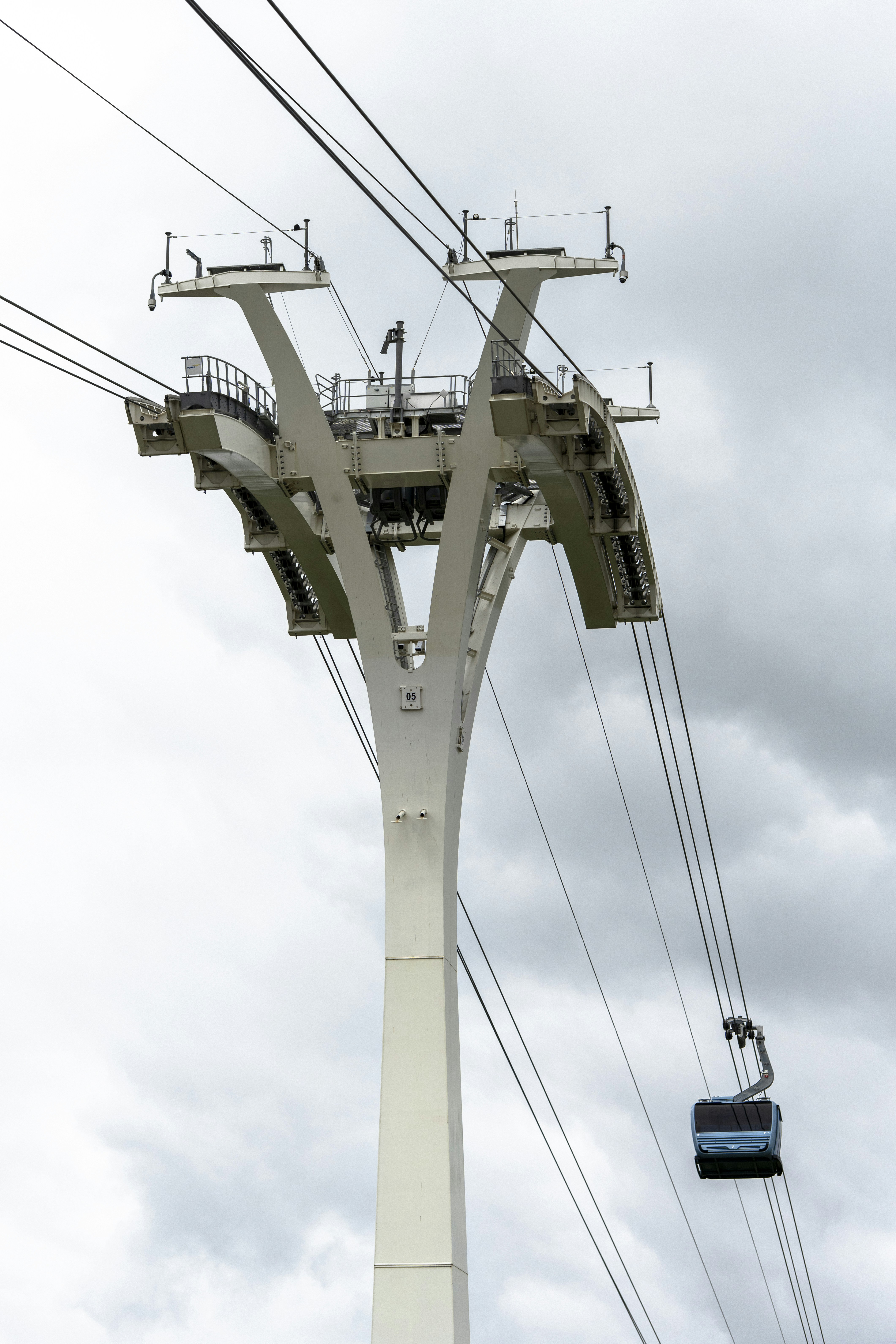 Cable car tower and car against a cloudy sky.