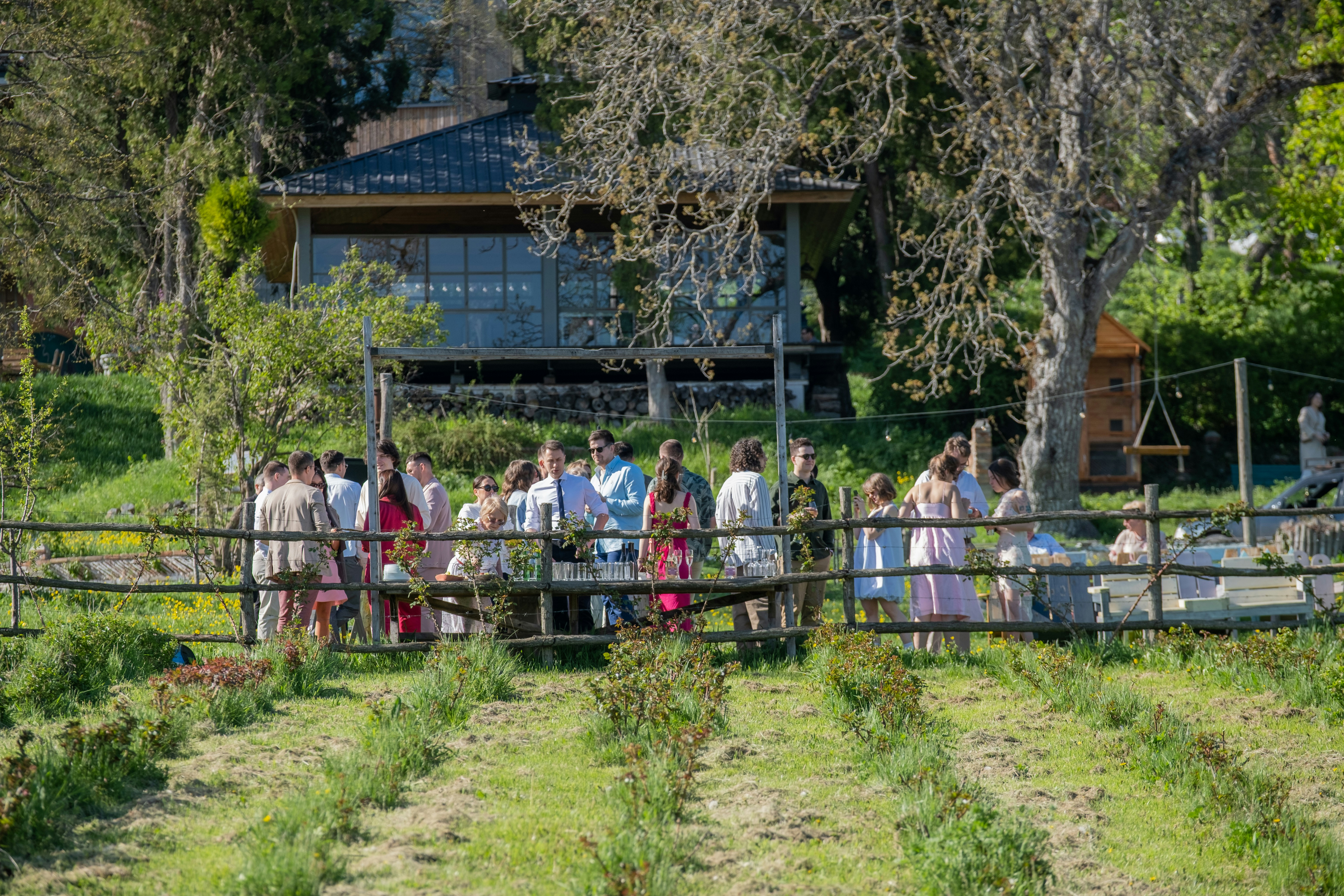 Guests gather outside a wooden building in nature.