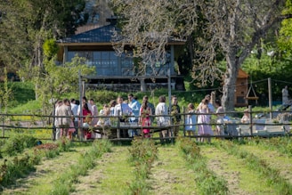 Guests gather outside a wooden building in nature.