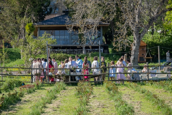 Guests gather outside a wooden building in nature.