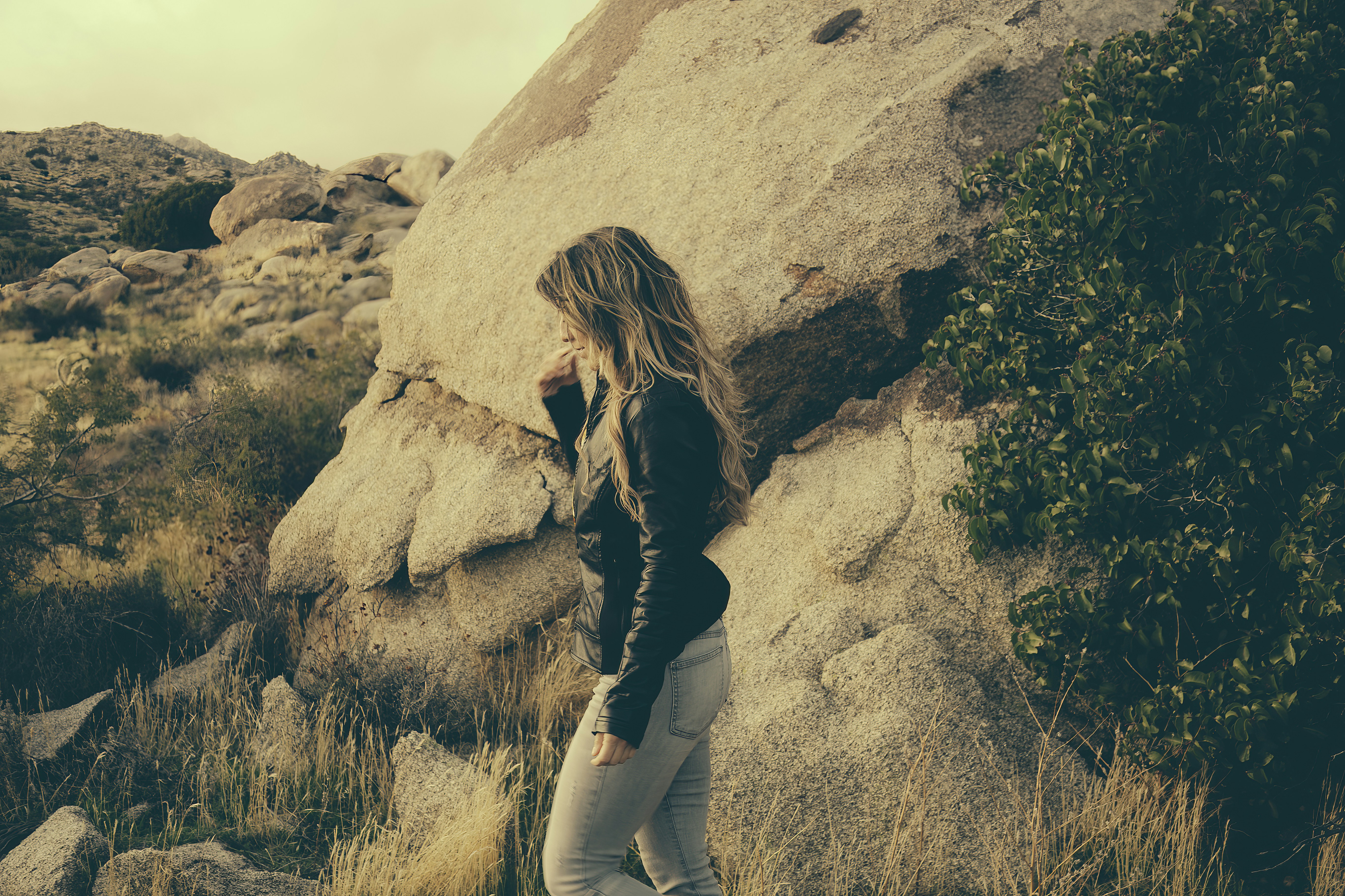 Woman stands near a big rock outdoors.