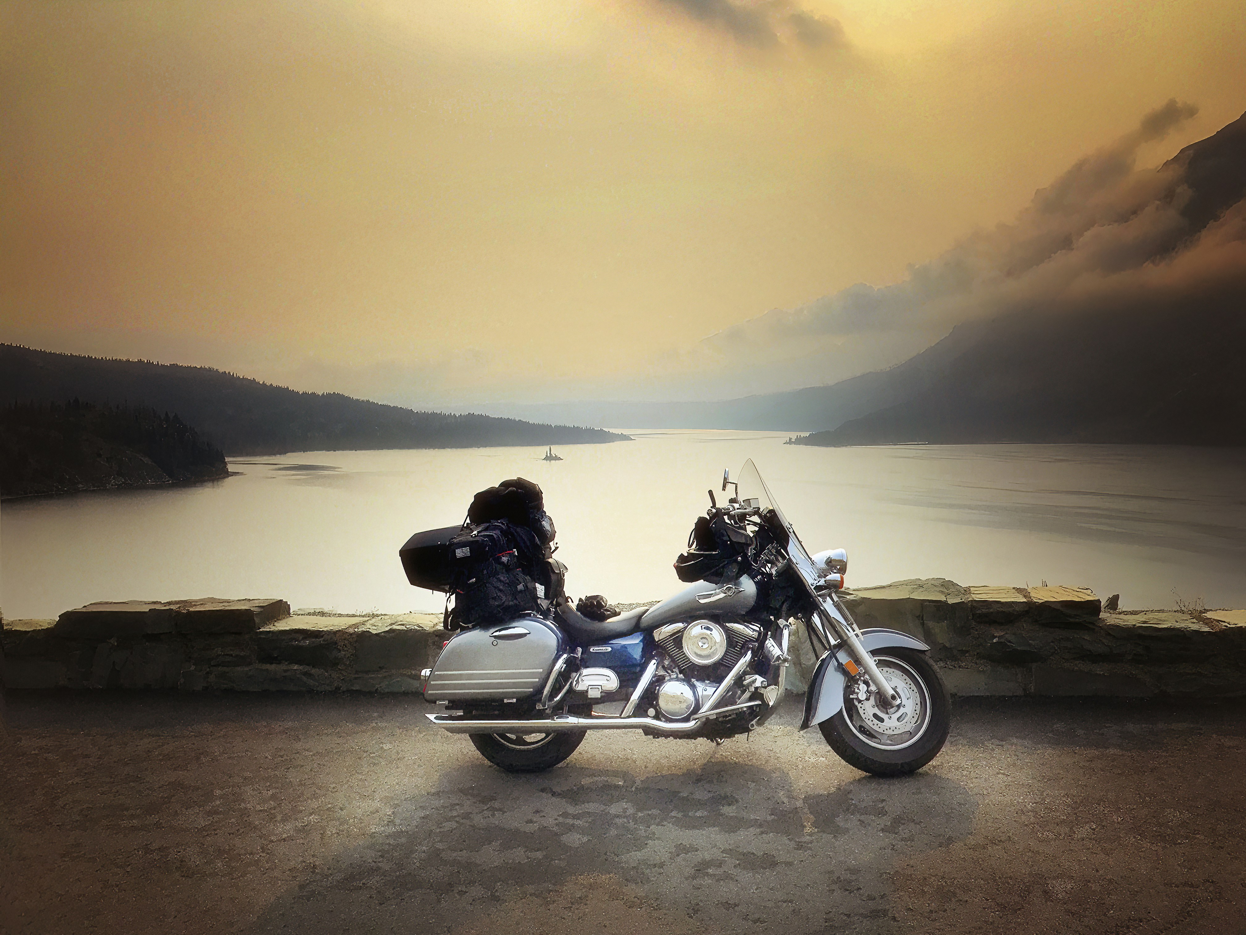 Motorcycle parked near a scenic lake at sunset.