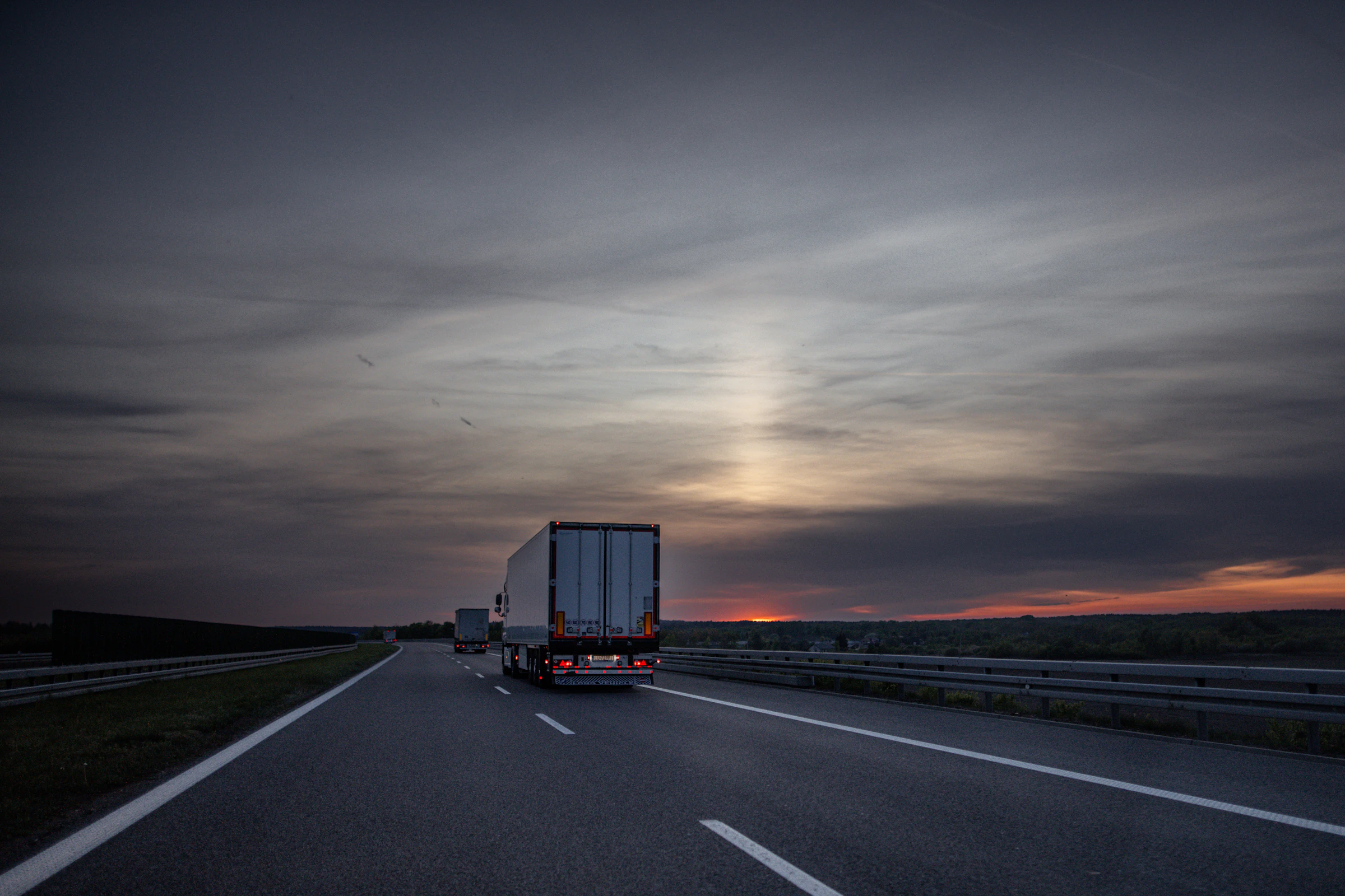 Trucks driving down the highway at sunset