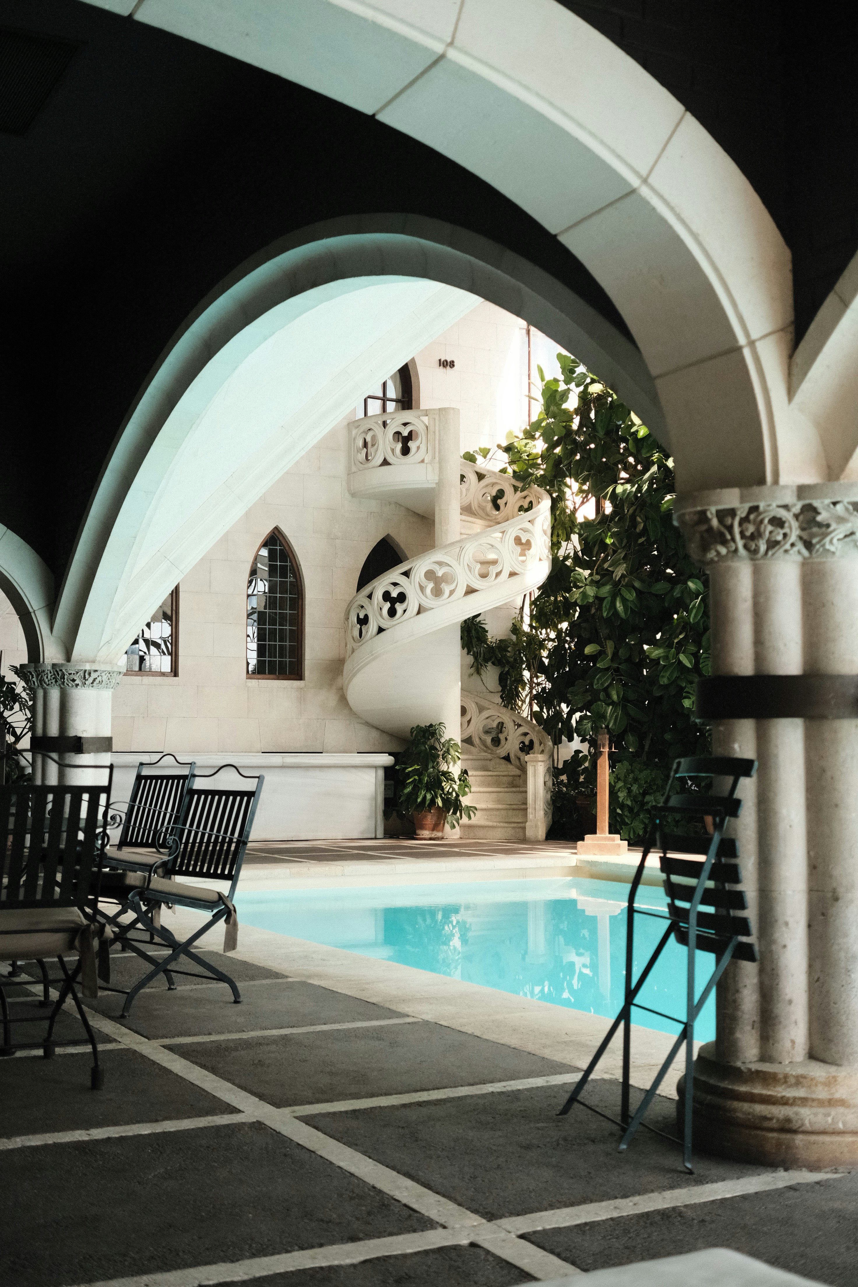 Una piscina y una escalera de caracol dentro de un arco.