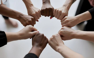 People of diverse skin tones fist bumping in a circle.