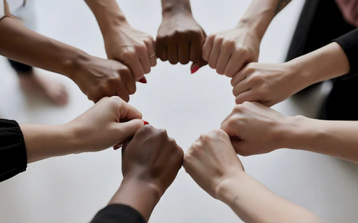 People of diverse skin tones fist bumping in a circle.