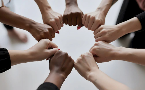 People of diverse skin tones fist bumping in a circle