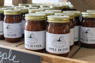 Apple butter jars are displayed on a wooden shelf.