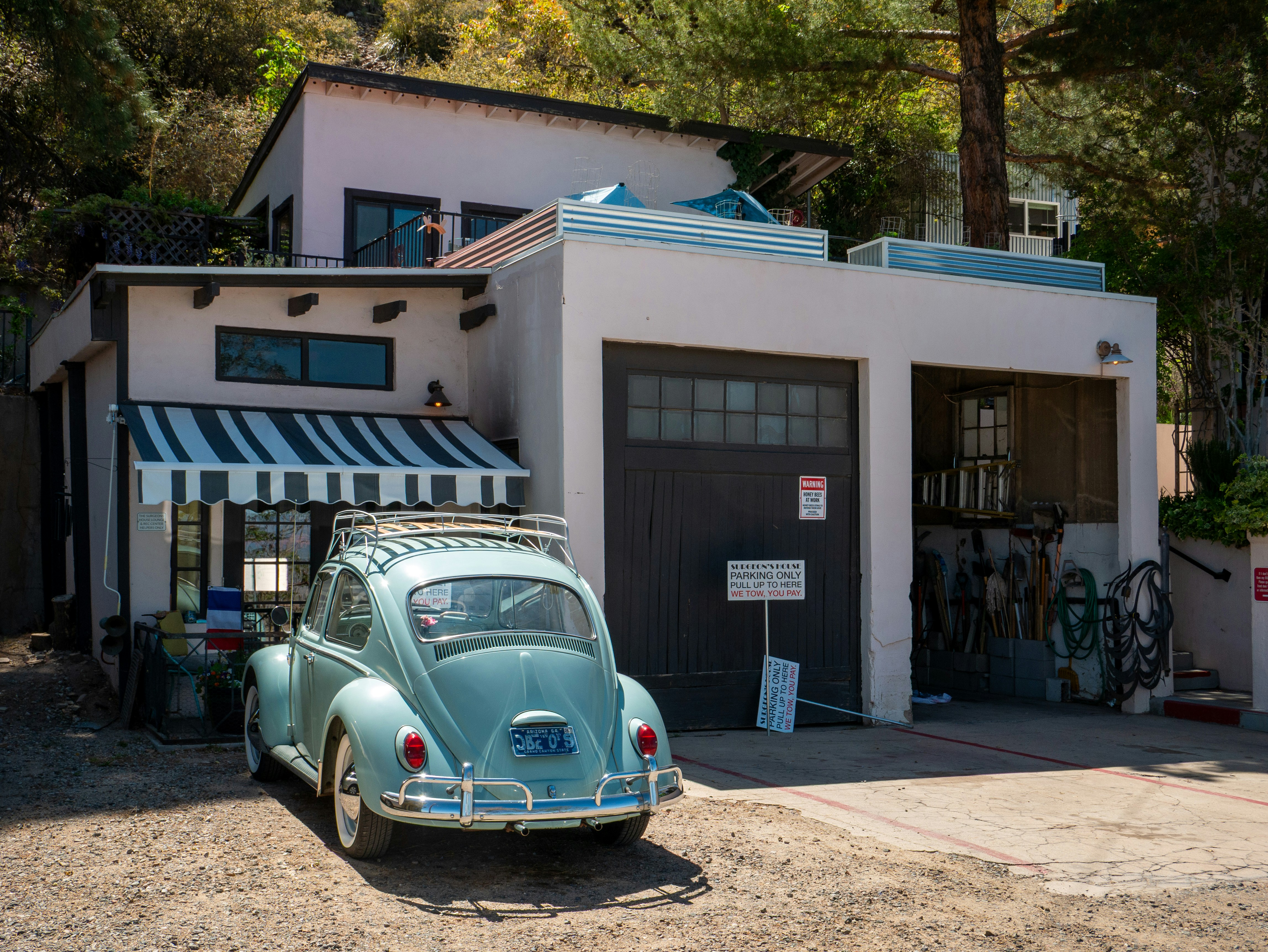A blue vw beetle parked in front of a garage.