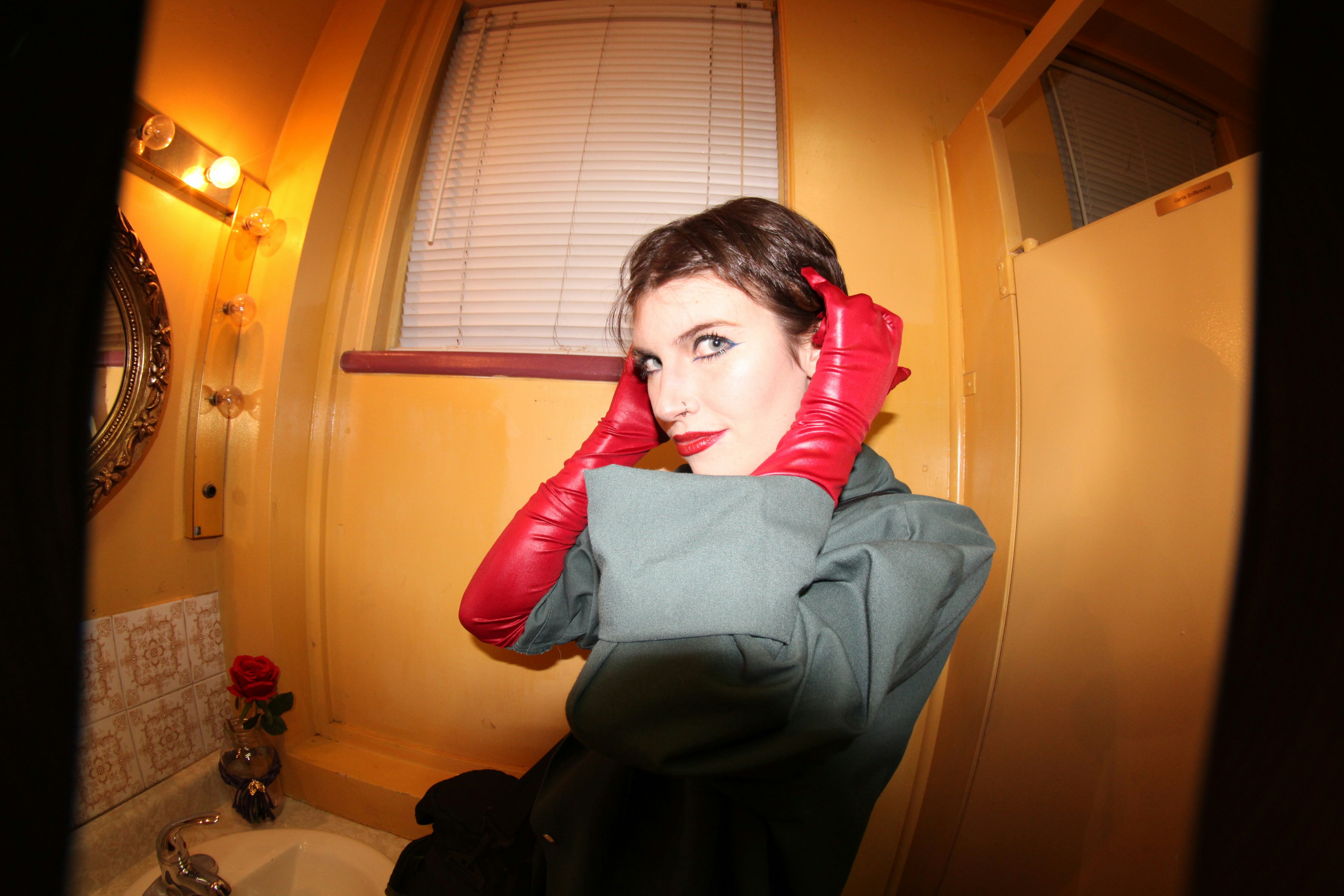Woman wearing gloves poses in a bathroom.