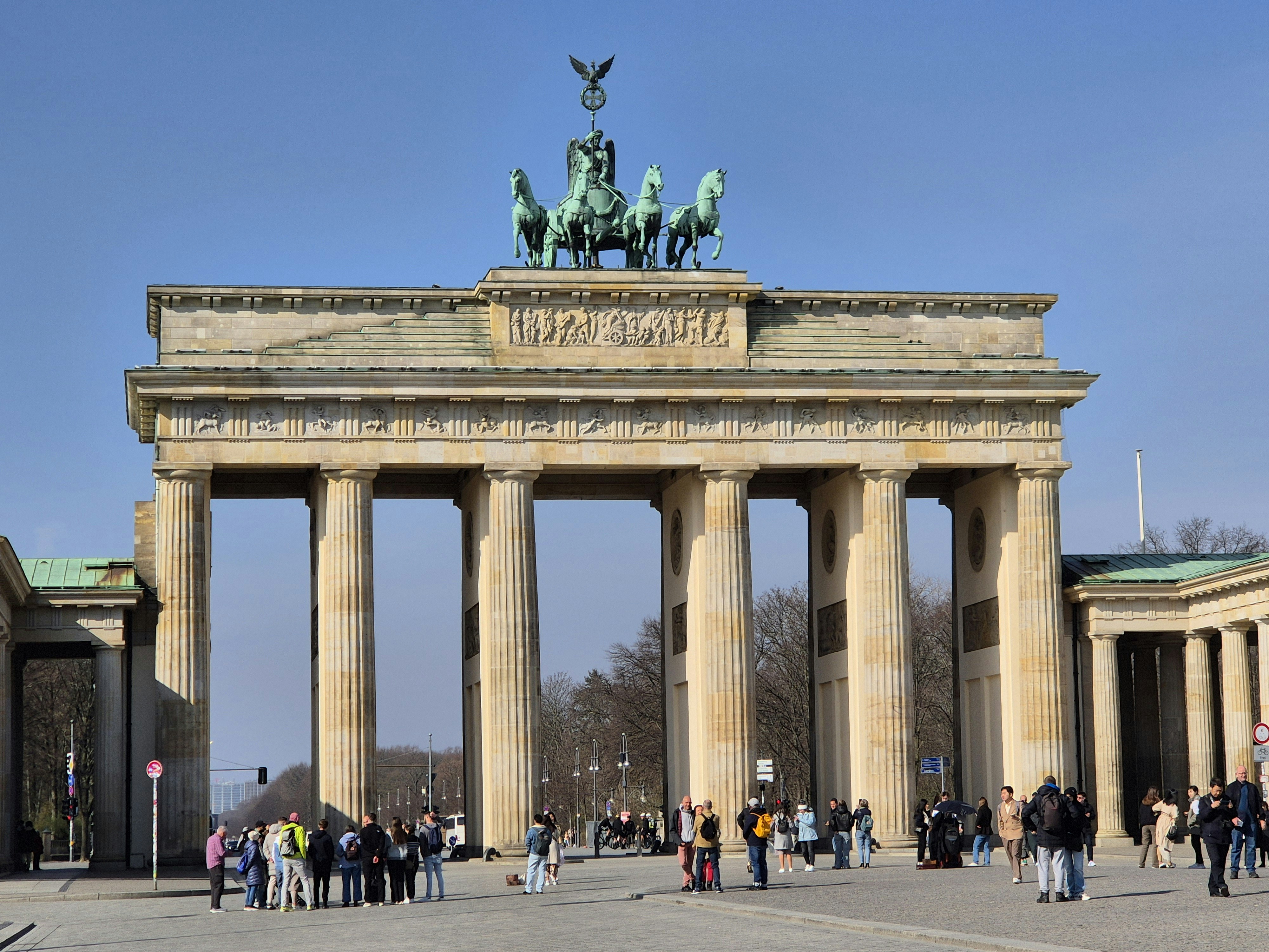 The brandenburg gate stands tall on a sunny day.