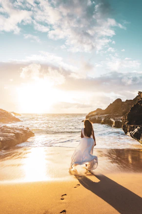 Woman walks on the beach as the sun sets.