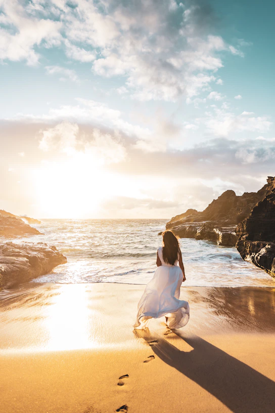 Woman walks on the beach as the sun sets.