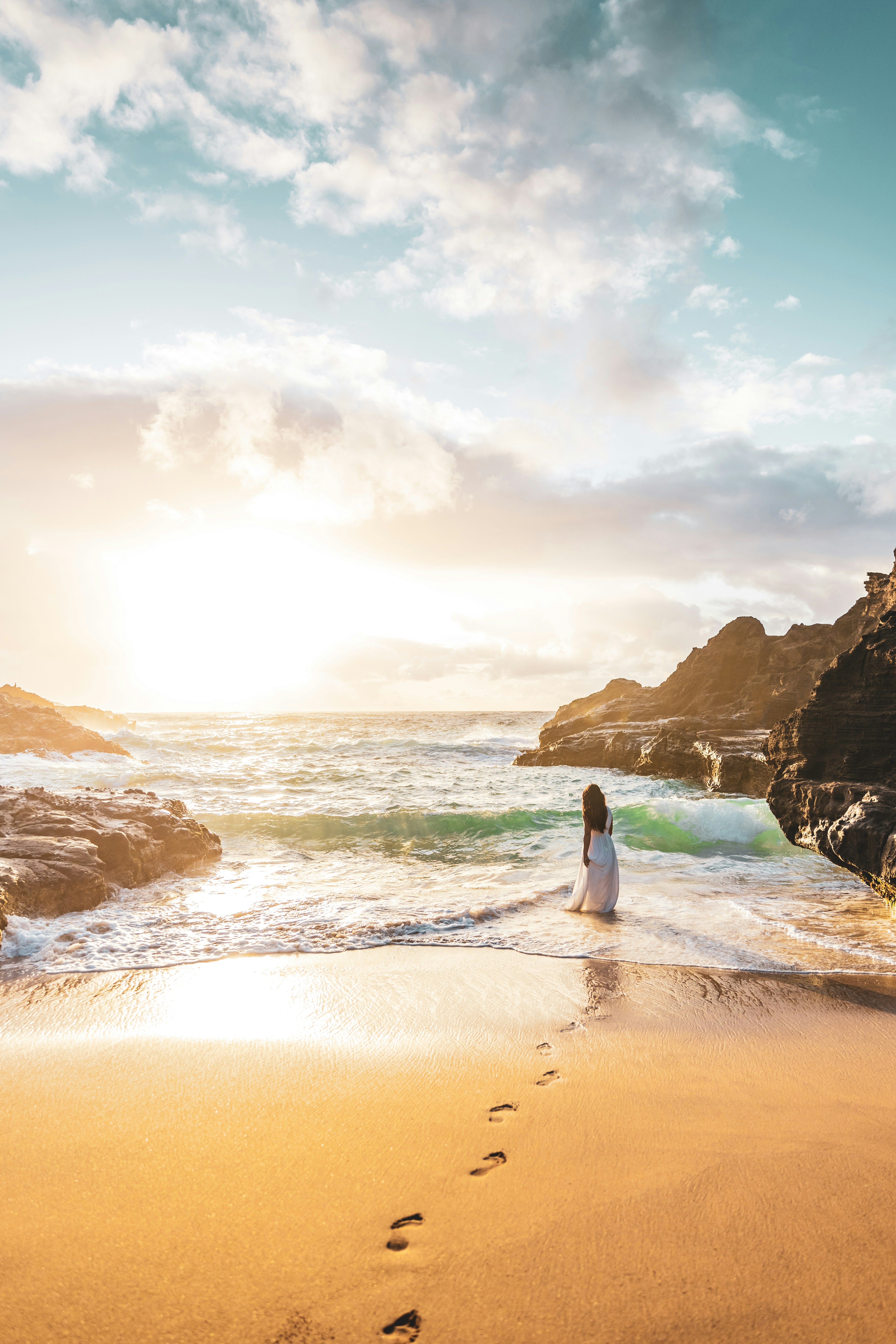 Woman stands at the beach, gazing at the ocean.