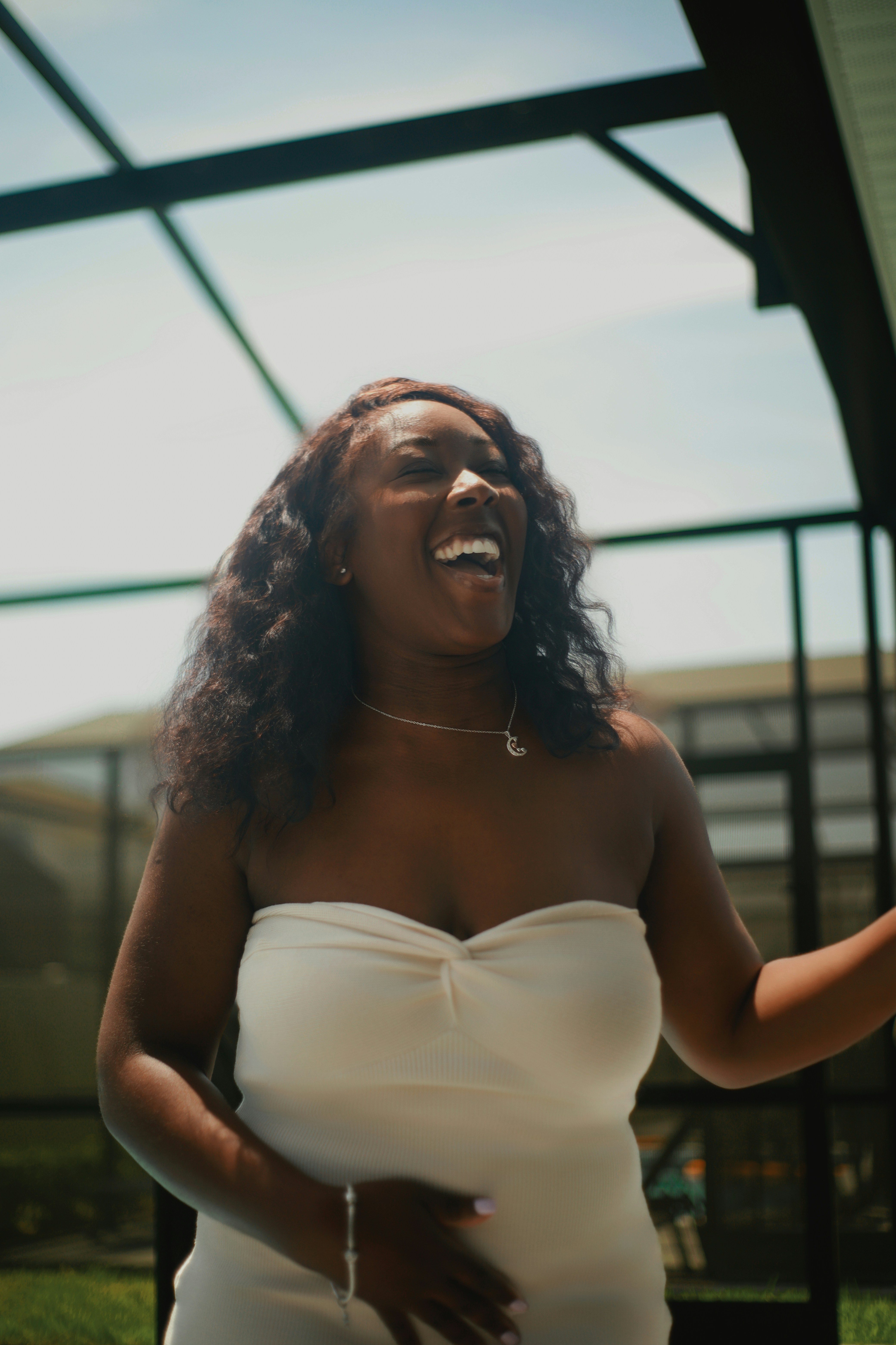 Happy woman in a white dress smiles widely.