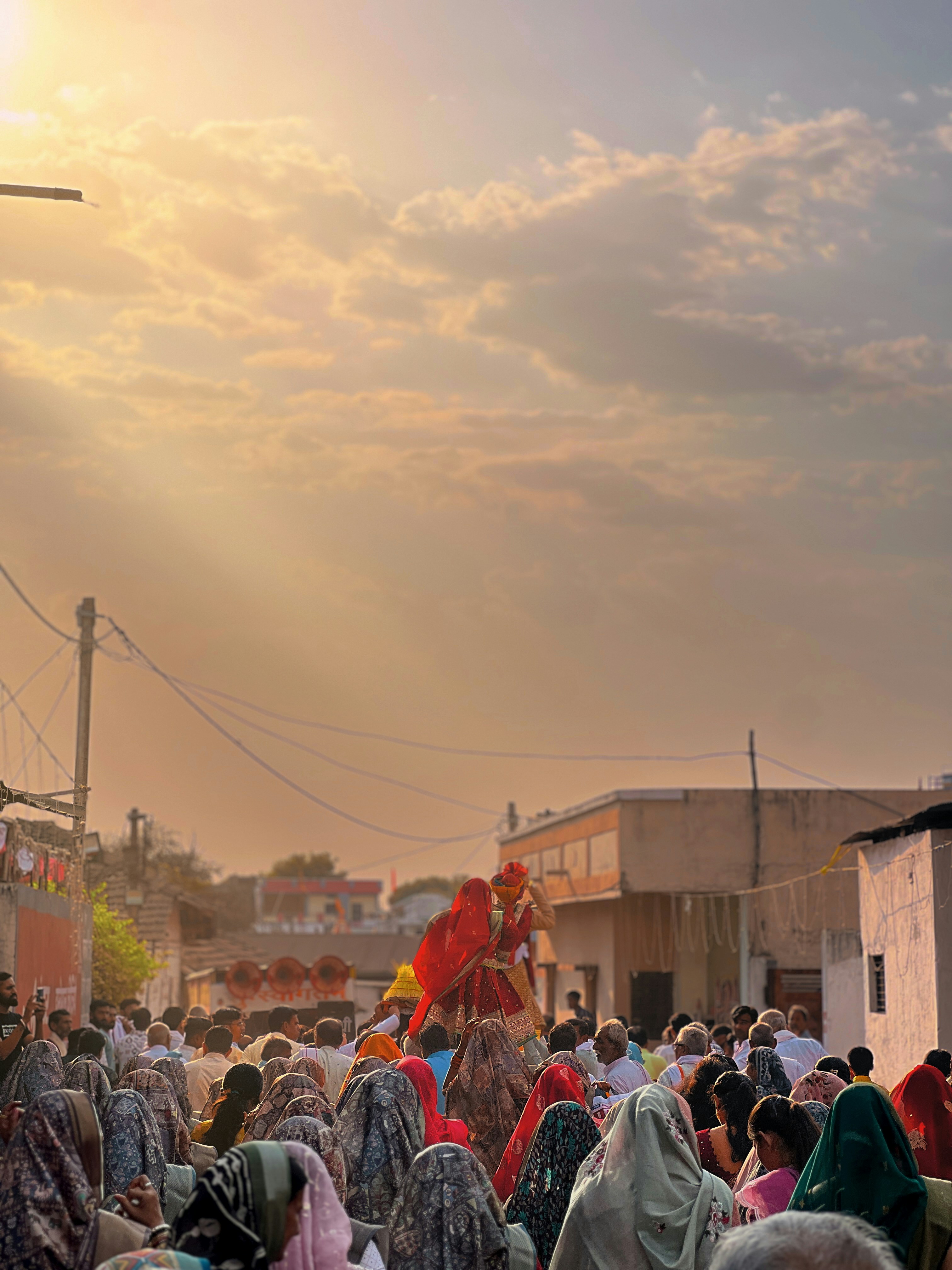 Sebuah parade melewati jalan yang ramai saat matahari terbenam.