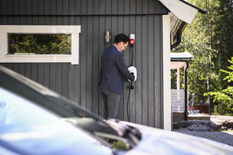 Man plugs in an electric vehicle charging cable