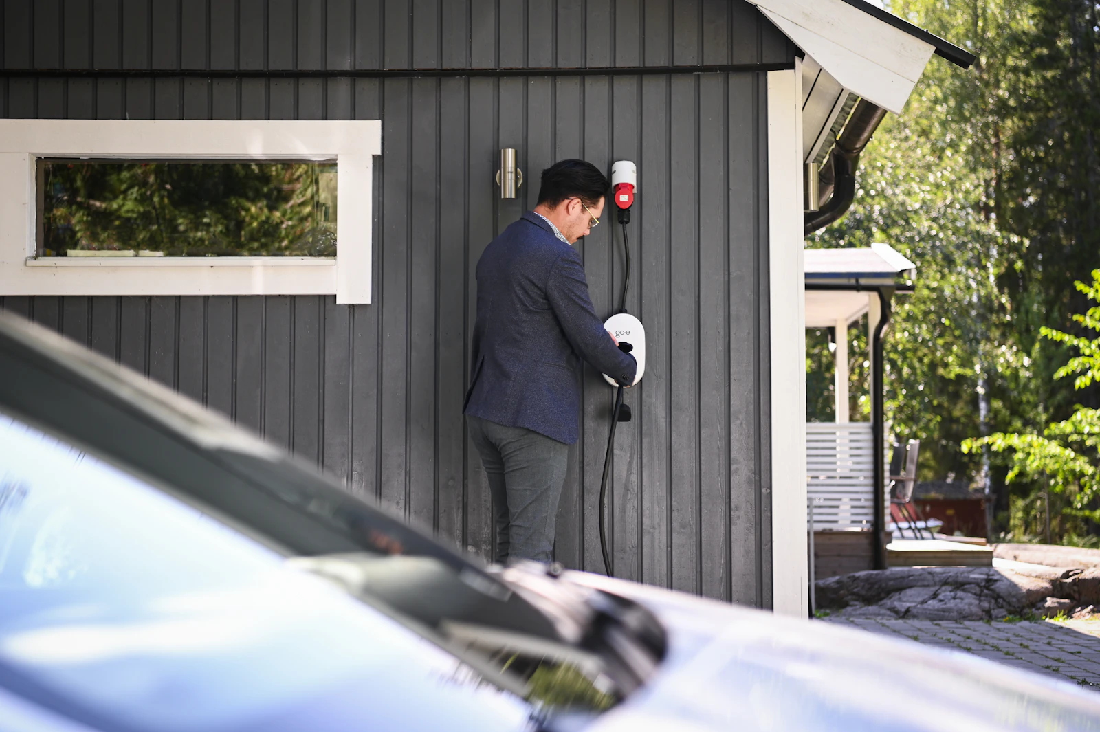 Un client branche le câble de sa borne de recharge louée auprès de Solaris Charge